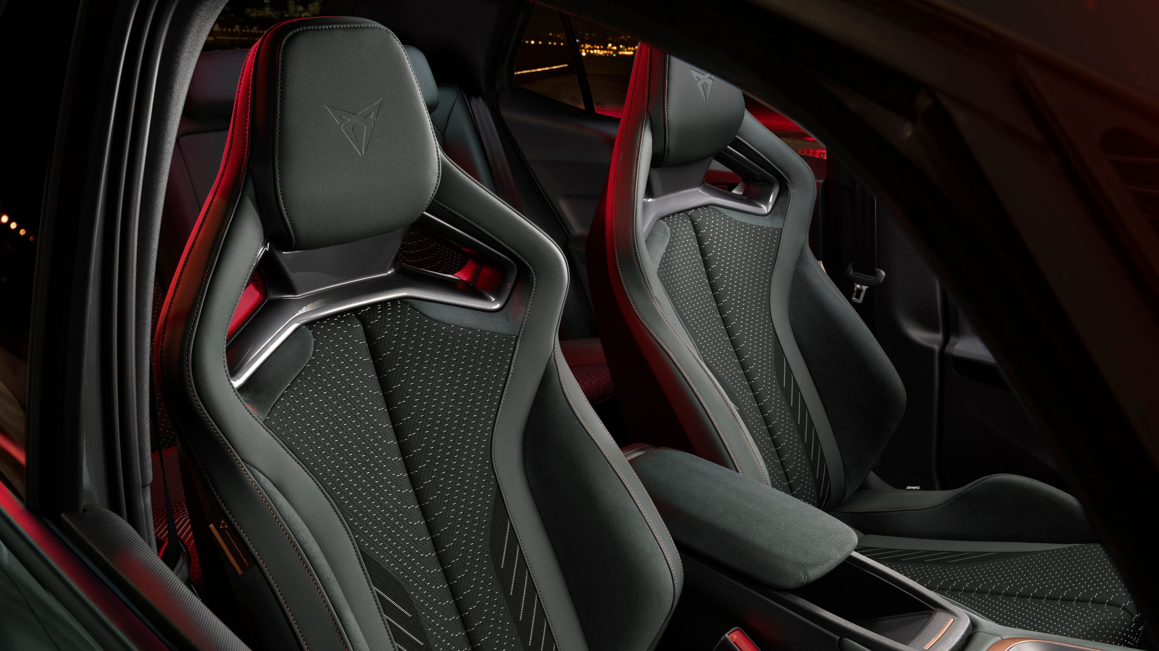 Športna sprednja sedeža modela CUPRA Born z izrazito bočno oporo in perforiranim oblazinjenjem. Notranjost dopolnjuje rdeča ambientalna osvetlitev, ki poudarja dinamičen in sodoben značaj vozila.