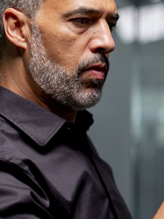 Moški riše s suho piši markerjem po stekleni tabli, na kateri so skice različnih oblik. 