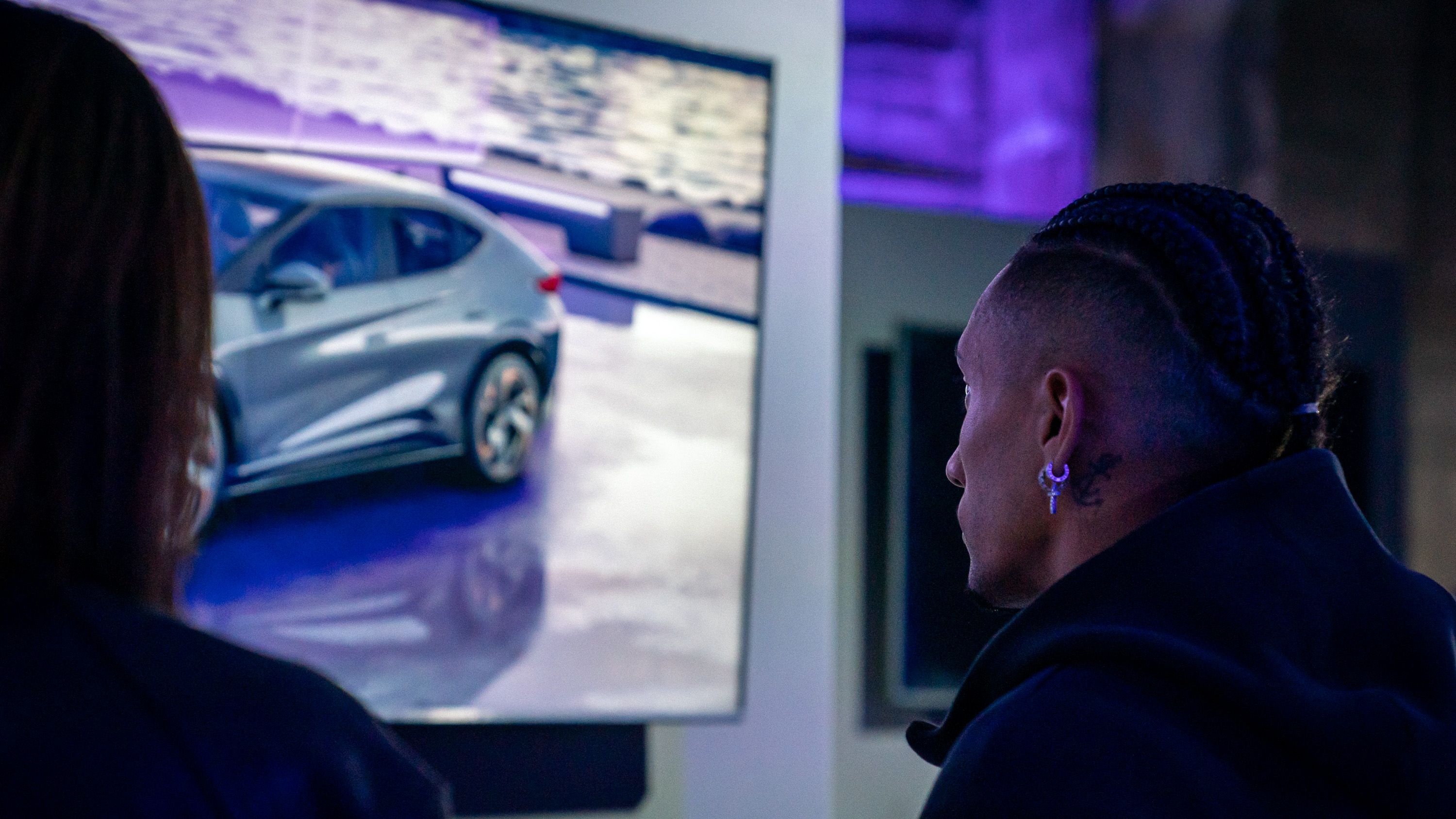 Dva igralca FC Barcelona opazujeta zaslon, ki prikazuje avtomobil CUPRA Terramar. Okolje je osvetljeno z modrim svetlobnim efektom.