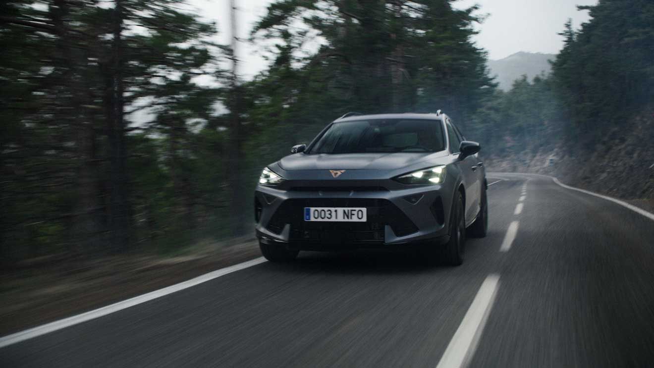 CUPRA Formentor vozi po ovinkasti gozdni cesti v naravnem okolju. Dinamičen prizor poudarja zmogljivost in stabilnost vozila med vožnjo.
