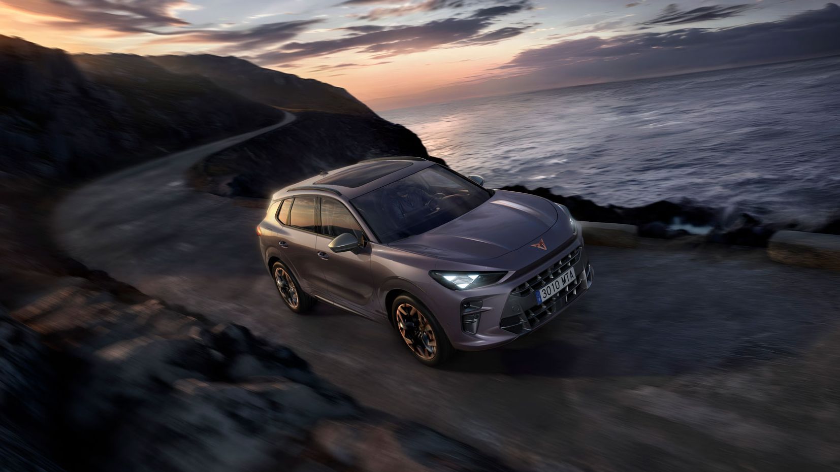 CUPRA Terramar vozi po obalni cesti ob sončnem zahodu.