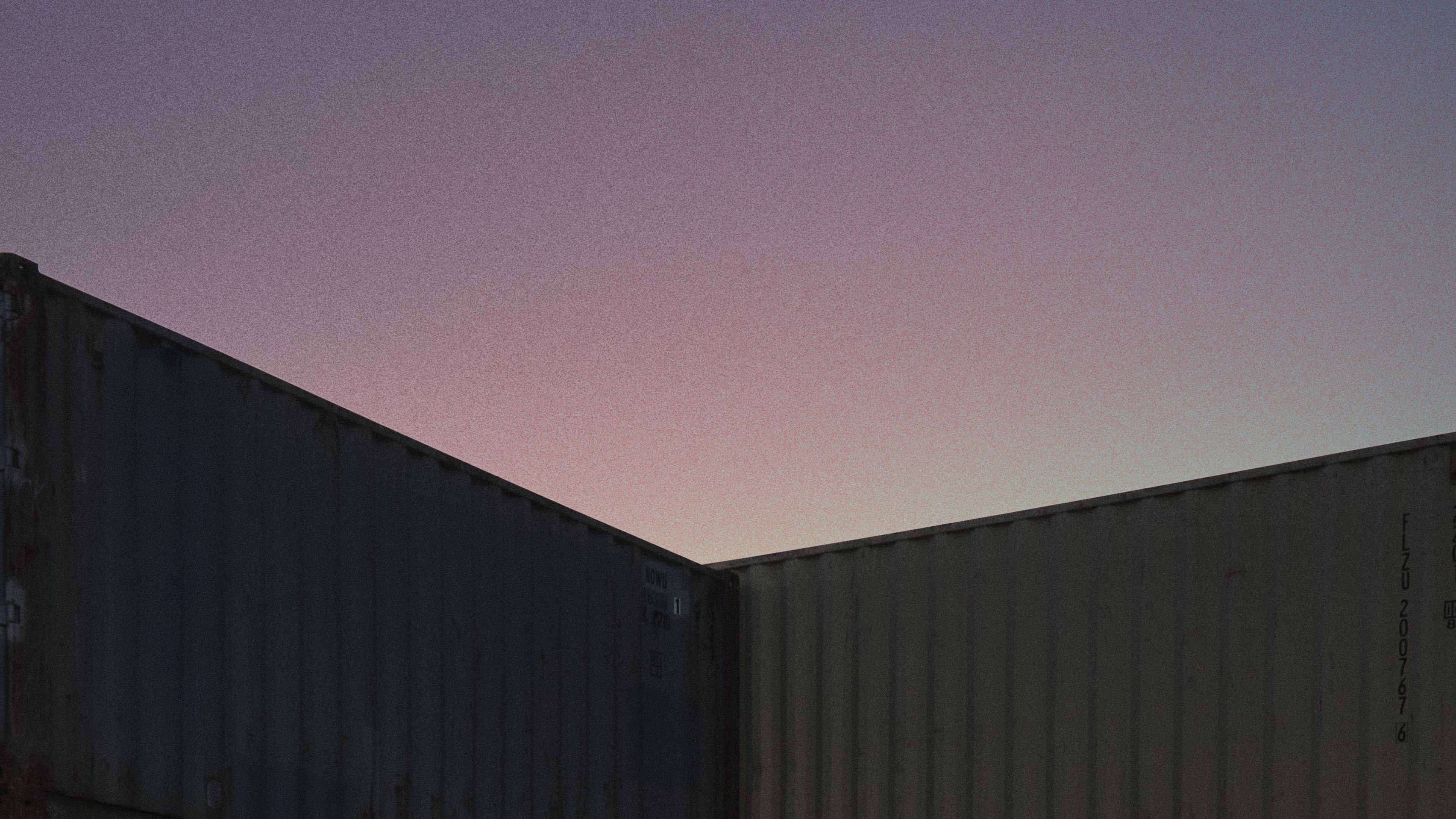 Tri robustni kovčki z izvlečnimi ročaji stojijo v industrijskem prostoru med ribiškimi mrežami, vrvmi in bojami, v ozadju so vidni kovinski kontejnerji.