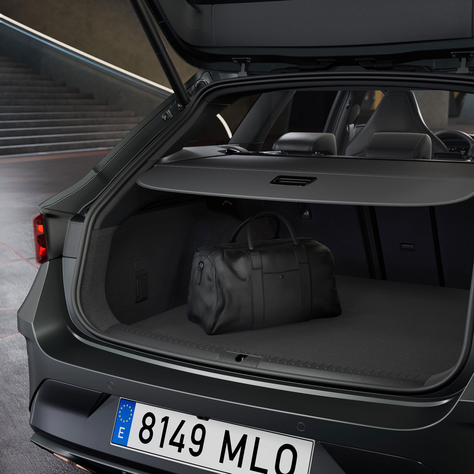 Odprt prtljažnik avtomobila CUPRA LEON SPORTSTOURER, v katerem je črna športna torba. Na zadnji strani avtomobila je nameščena evropska registrska tablica. V ozadju je viden sodoben, večstopenjski prostor.