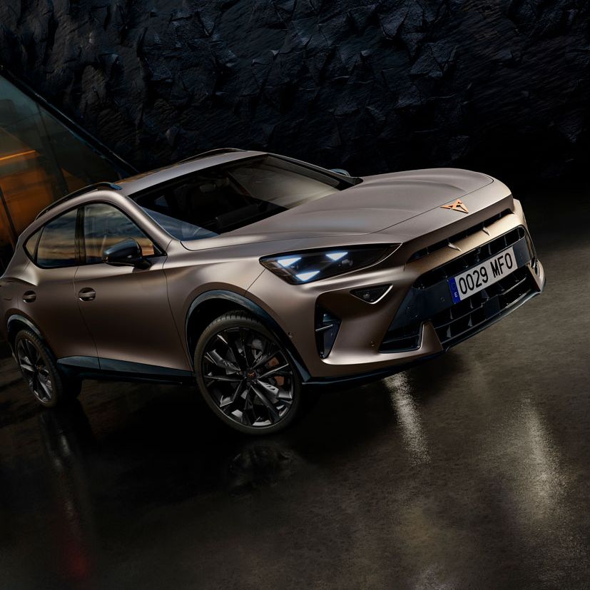 CUPRA Formentor PA v futurističnem okolju zatemnjenih tonov. Avto je parkiran na temnem, zrcalno gladkem tleh pred stavbo s teksturo stene. V ozadju je mestno obzorje ob sončnem zahodu.