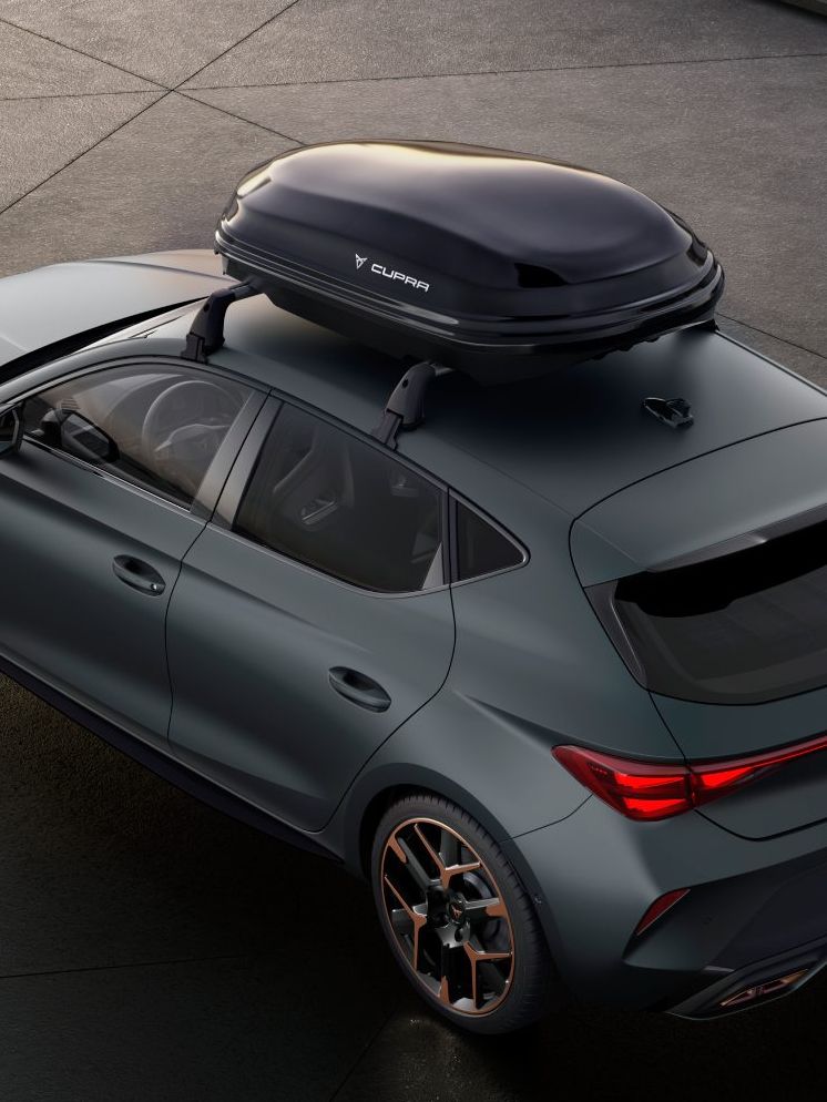 Sivi avtomobil CUPRA Leon PA, parkiran na betonski površini, ima na strehi kovček za shranjevanje.