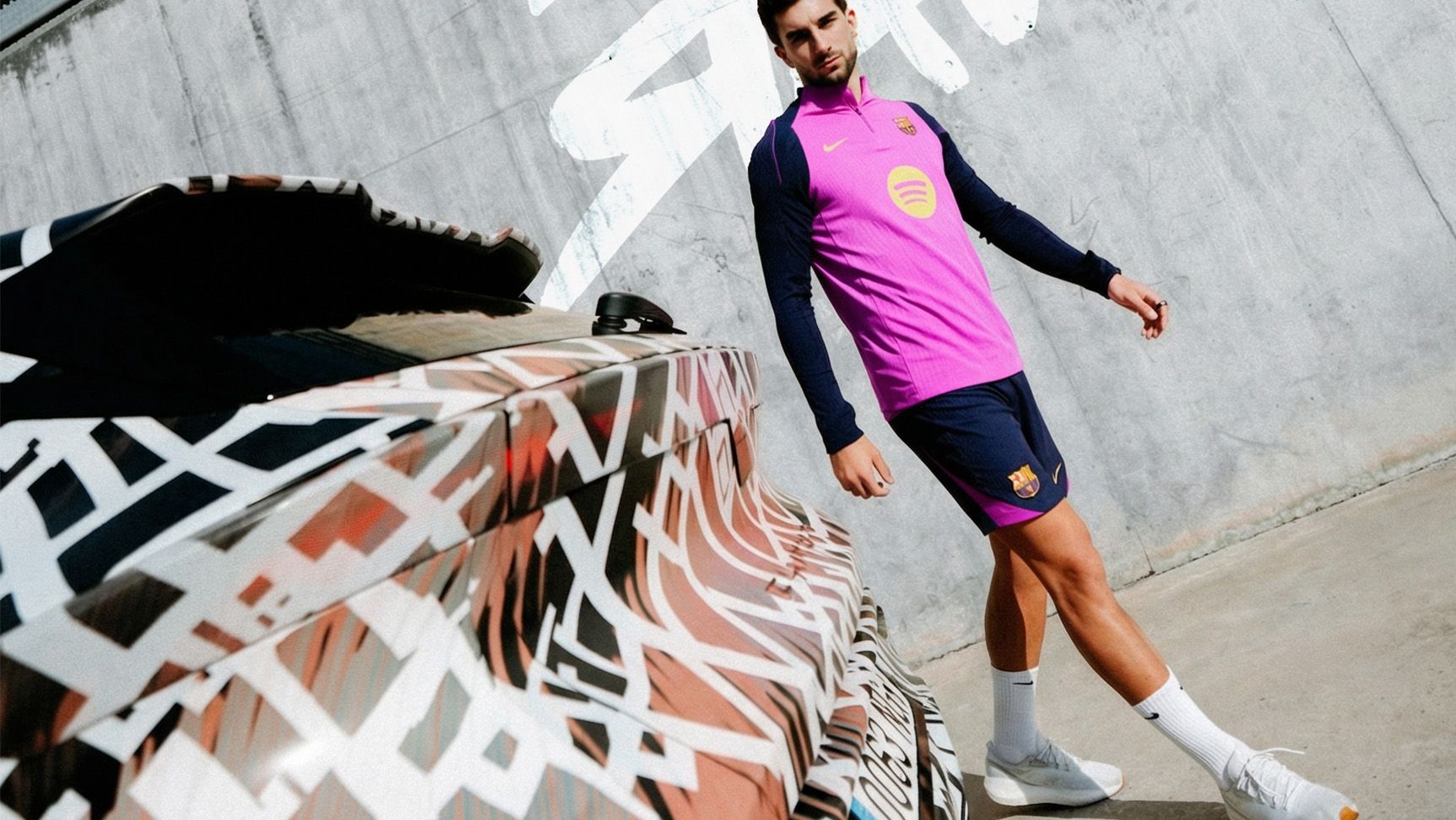 Nogometaš FC Barcelona v roza dresu hodi poleg CUPRA Ravala. V ozadju napis: BEYOND REBEL, RAVAL. 