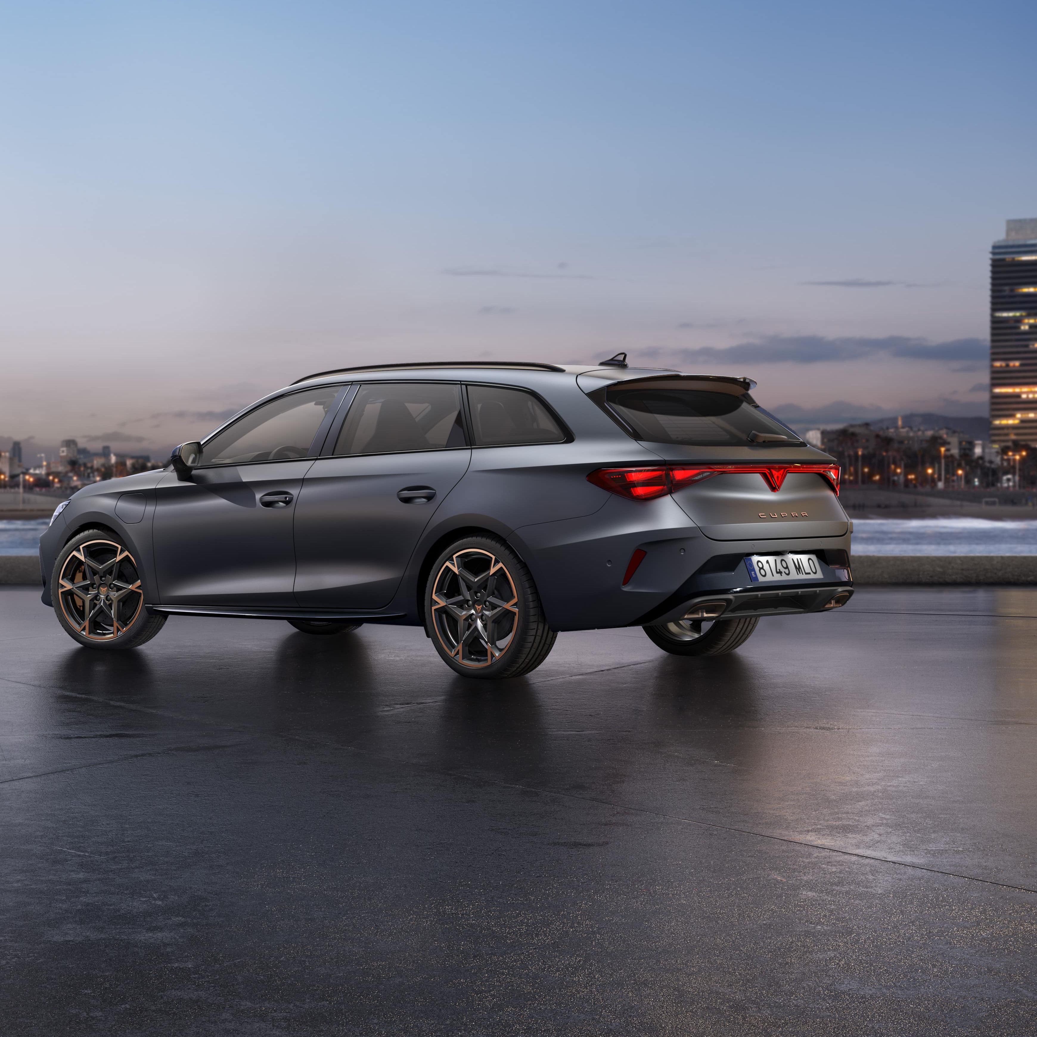 CUPRA LEON SPORTSTOURER stoji ob obali ob sončnem zahodu. V ozadju je mestno obzorje z visokimi stavbami, mokra površina pod vozilom pa odseva nebo.