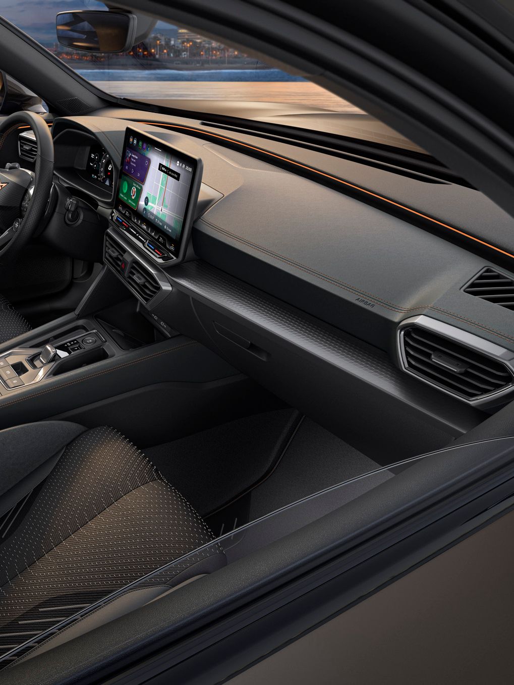 Notranjost sodobnega vozila CUPRA Formentor PA PHEV VZ z velikim zaslonom infotainment sistema, volanom in upravljalnimi elementi. Vozilo ima elegantne črne sedeže, skozi okna pa se vidi reka in osvetljeno mesto.