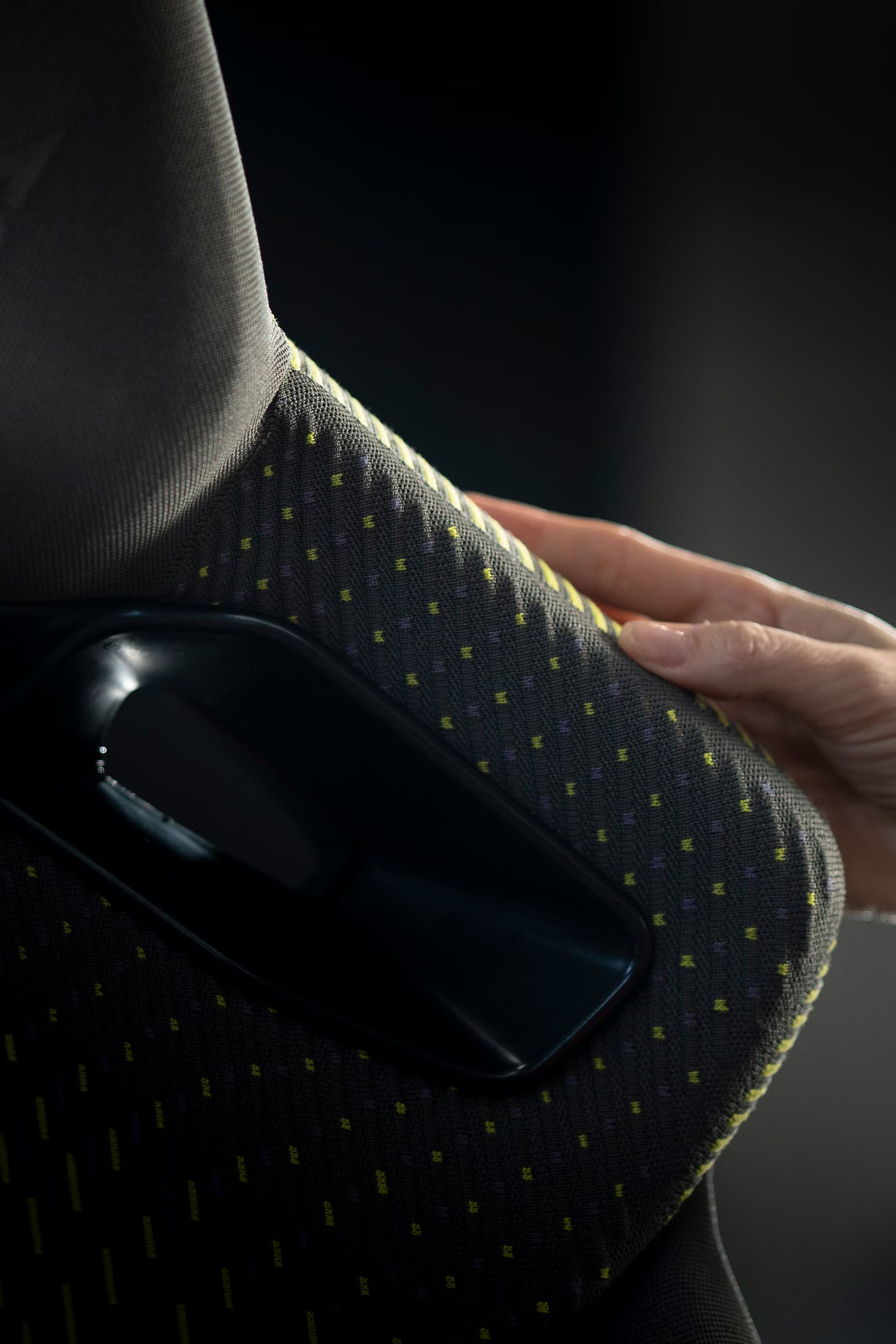 Roka se dotika tekstilnega materiala na naslonu sedeža z logotipom znamke CUPRA. Detajl poudarja strukturo tkanine, kakovost izdelave in premišljen dizajn notranjosti.