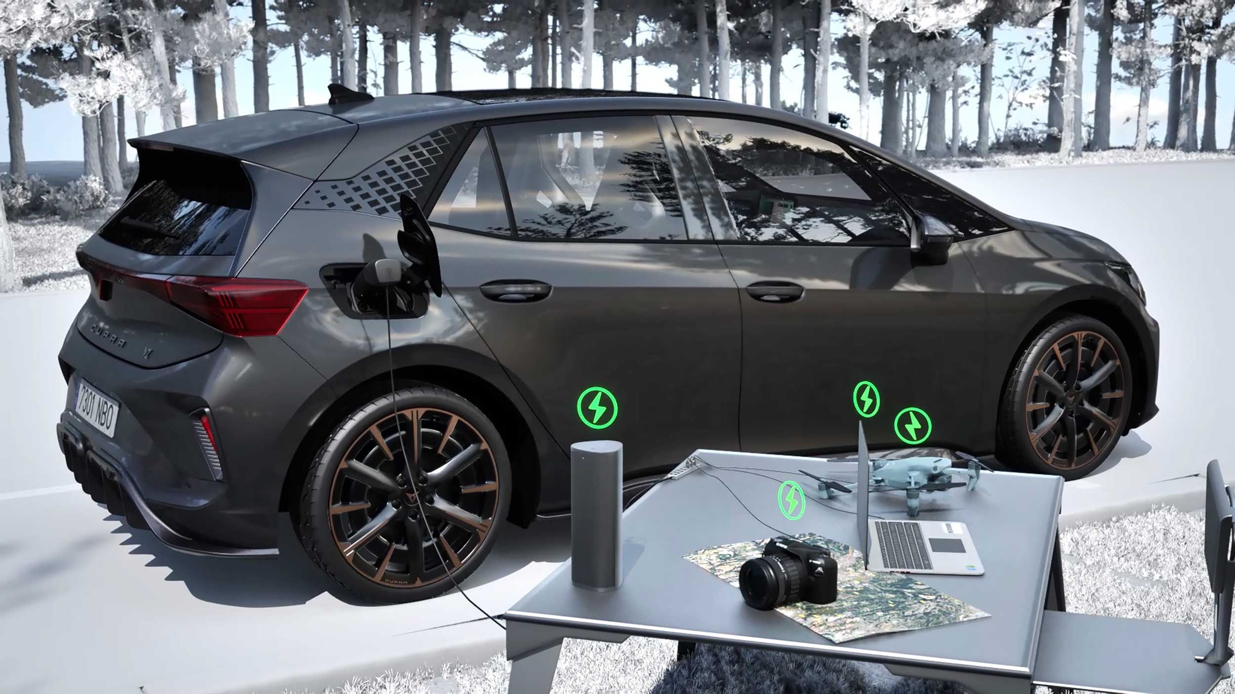 Temno siv električni CUPRA Born je parkiran ob gozdu in priključen na polnilni kabel. Ob avtomobilu stoji miza z razpostavljenim prenosnikom, fotoaparatom, zemljevidom in drugimi elektronskimi napravami. 