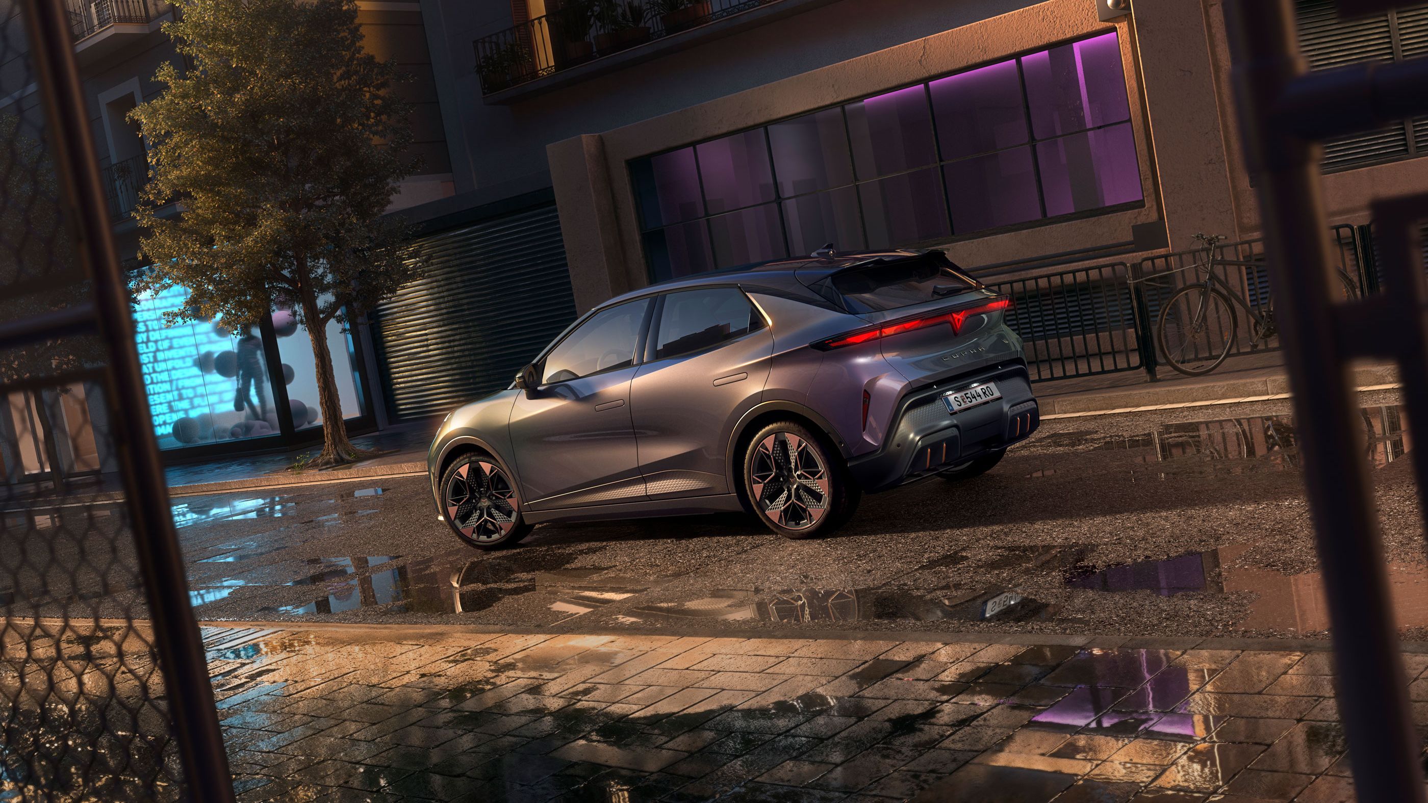 Pogled od blizu na zadek CUPRA Ravala VZ v plazemski barvi z 19-palčnimi platišči, parkiranega ponoči na mestni ulici.