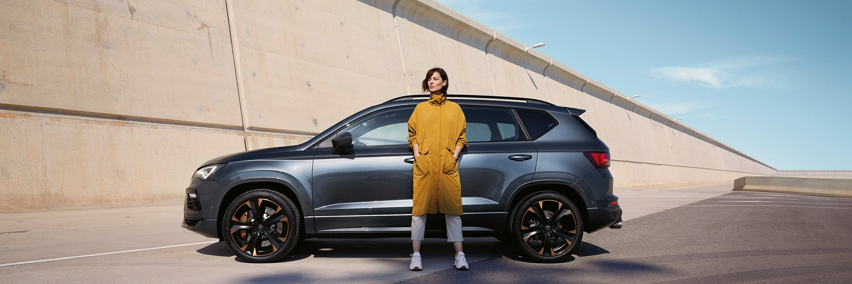Ein CUPRA Ateca in grau, eine Frau steht davor.