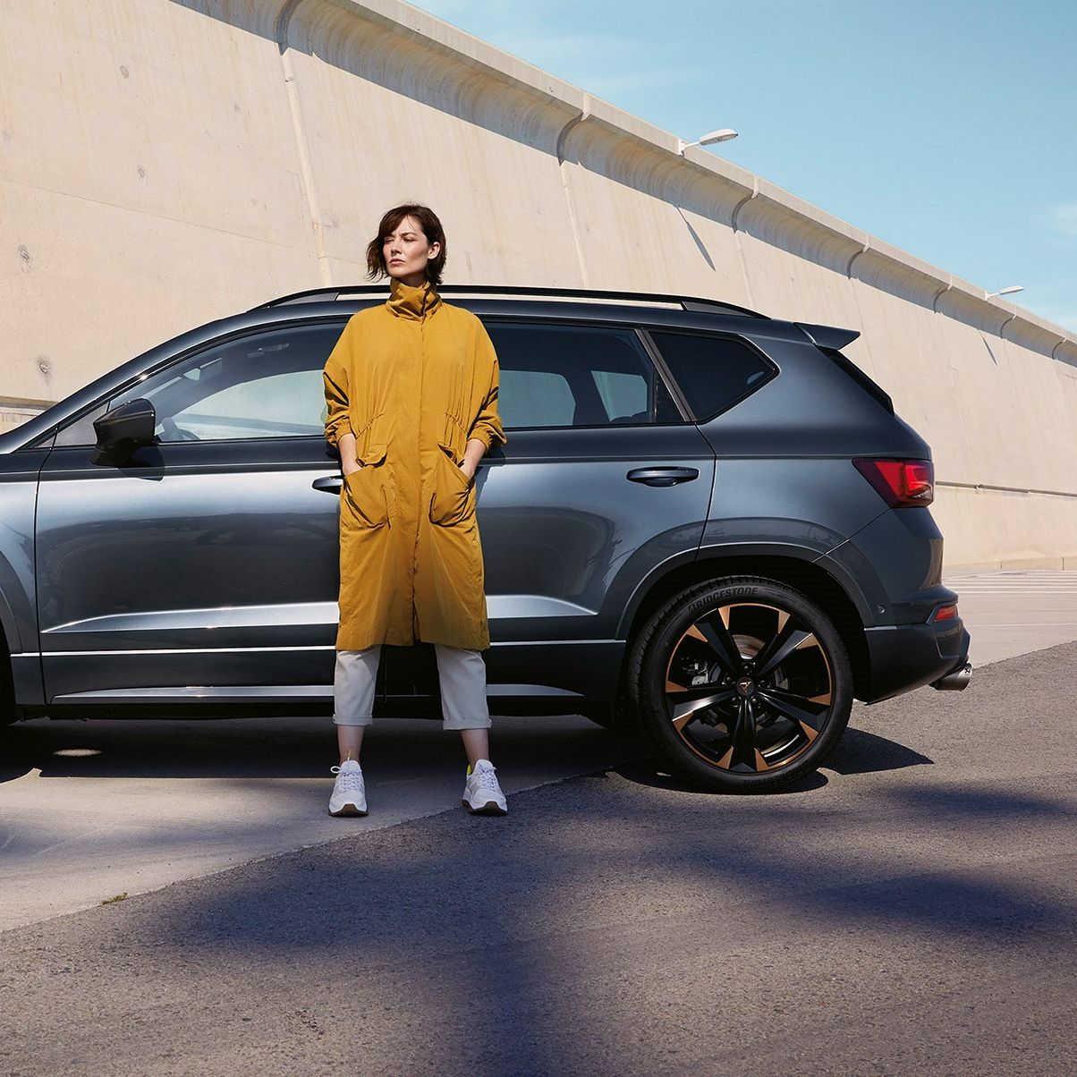Ein CUPRA Ateca in grau, eine Frau steht davor.