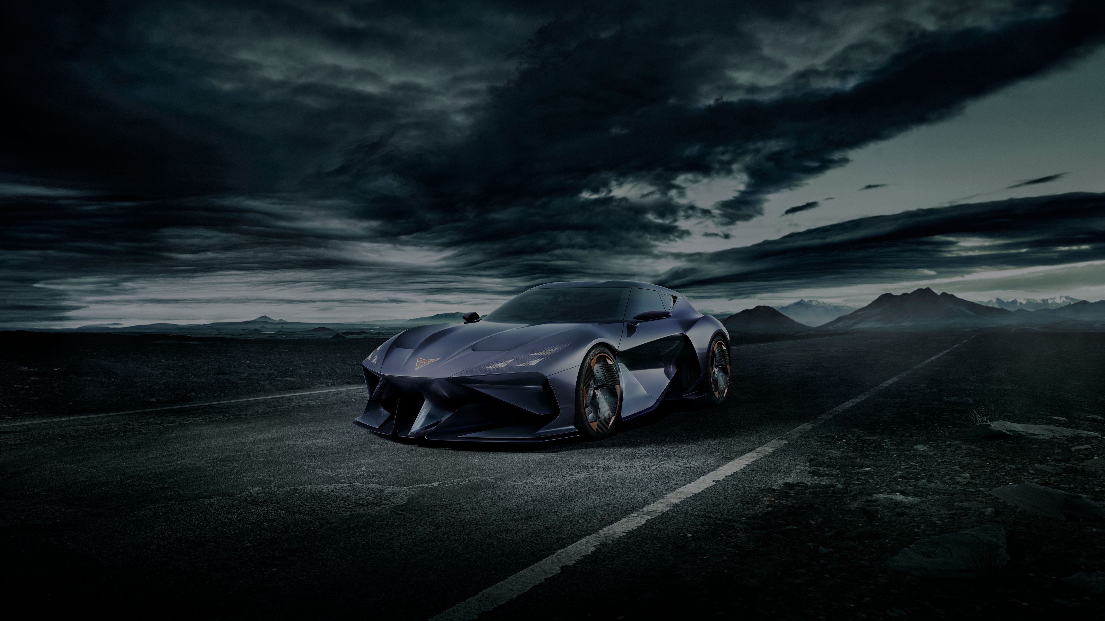 Temno vijolični CUPRA DarkRebel z izrazito sodobnim dizajnom vozi po cesti. Nebo je temno in oblačno, v ozadju pa so vidne gore.