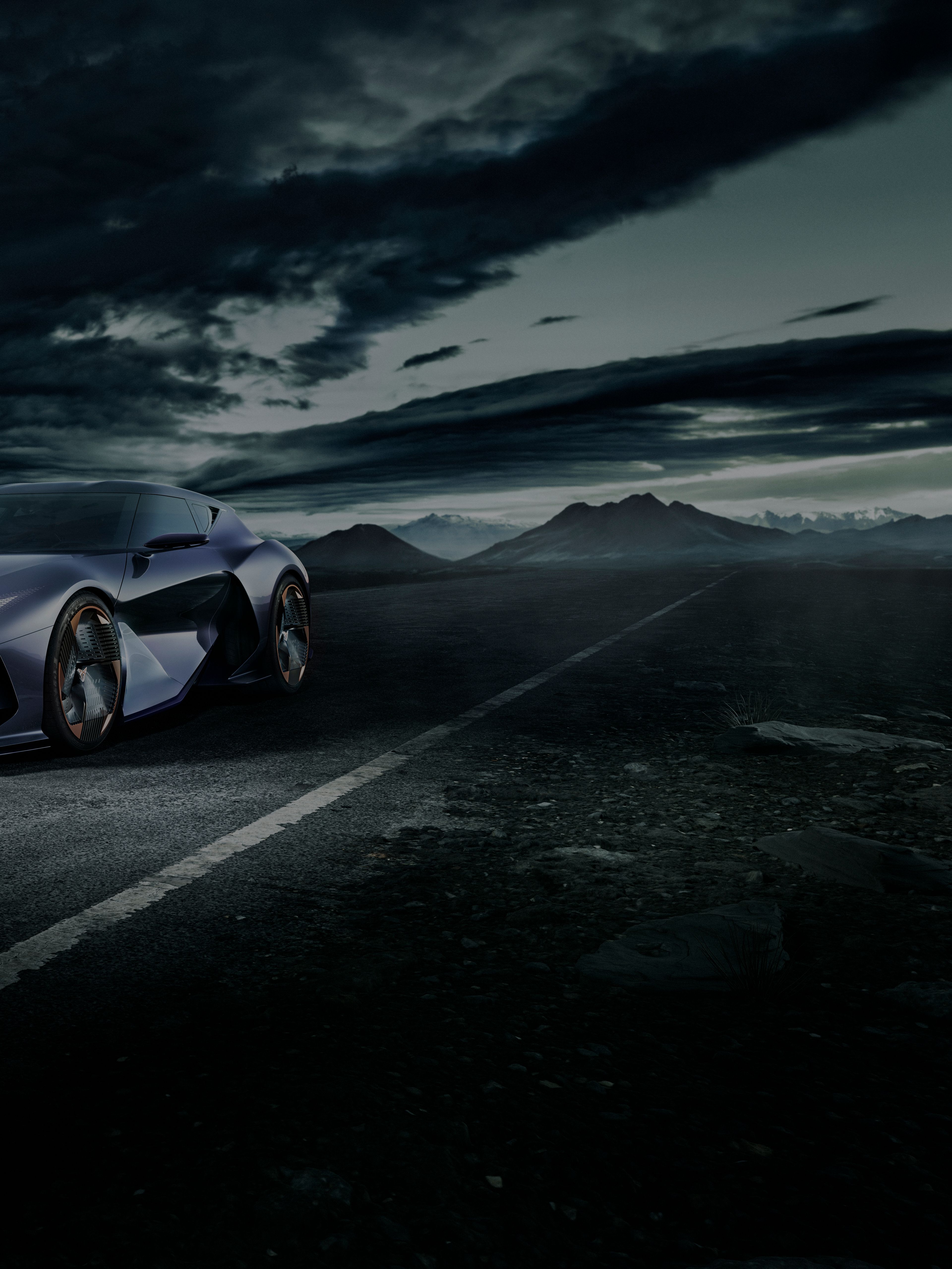 Temno vijolični CUPRA DarkRebel z izrazito sodobnim dizajnom vozi po cesti. Nebo je temno in oblačno, v ozadju pa so vidne gore.