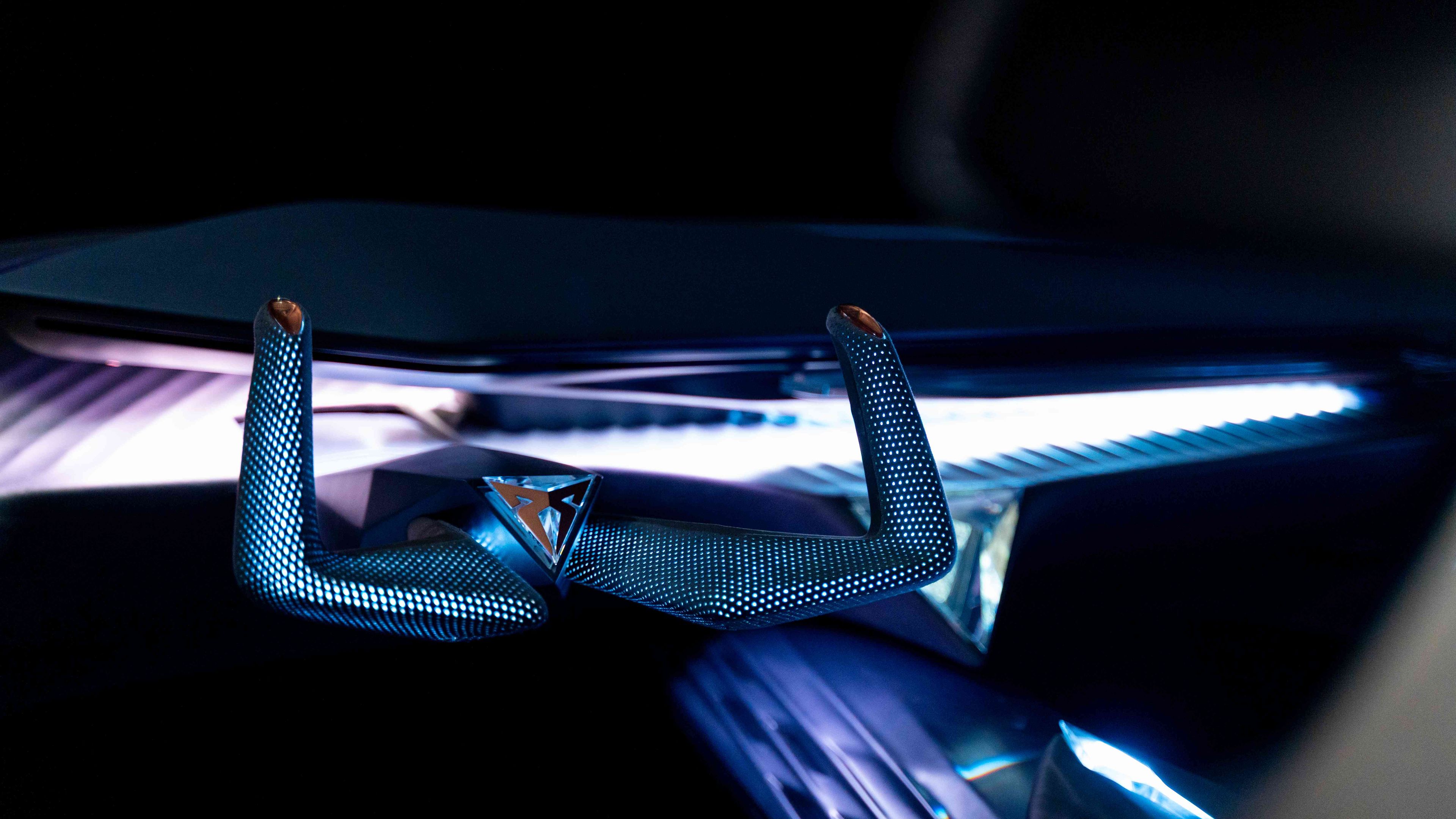 Futurističen volan avtomobila v temnem okolju, osvetljen z neonskimi lučmi. Volan ima aerodinamično obliko in moderno teksturo.