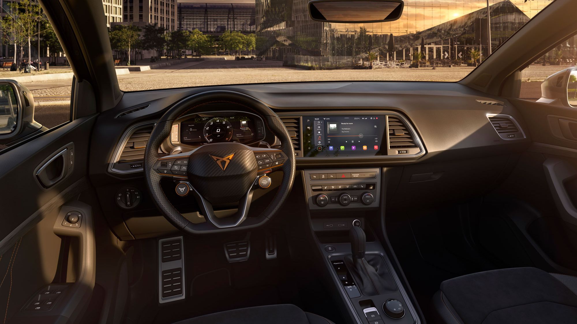 Notranjost sodobnega avtomobila CUPRA Ateca med sončnim zahodom. Armaturna plošča je opremljena z velikim zaslonom na dotik in vrsto kontrolnih gumbov. Sedeži in volan so luksuzno oblazinjeni.