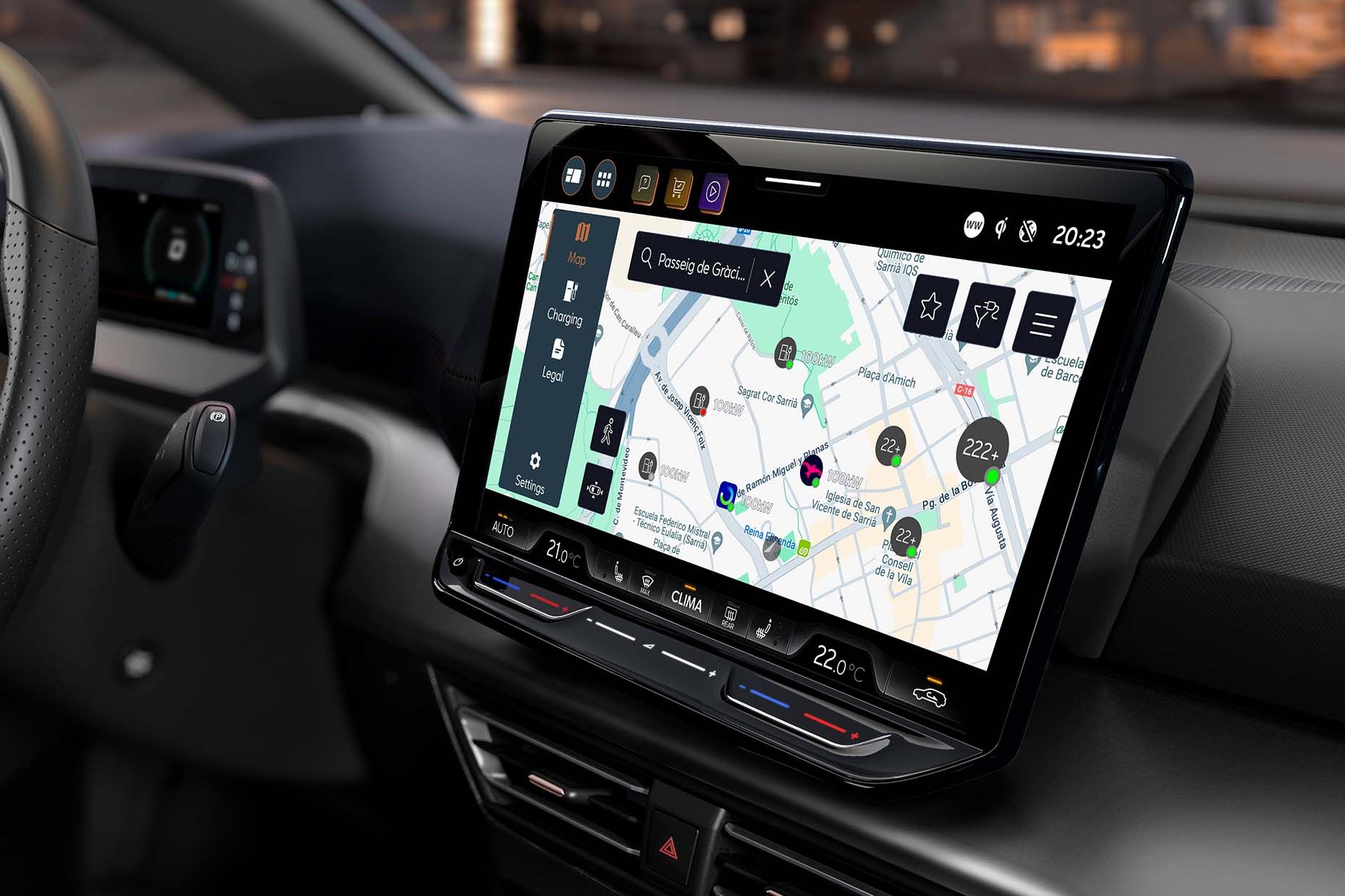 Notranjost sodobnega avtomobila CUPRA Born prikazuje volan in velik zaslon, na katerem je navigacijski sistem z zemljevidom. Osvetljena so mesta in točke zanimanja na zaslonu. V ozadju je vidno mesto ponoči.