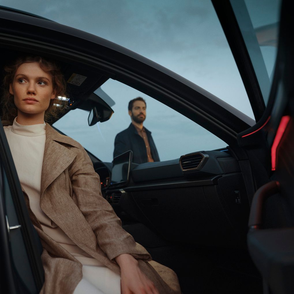Eine Frau sitzt bei geöffneter Beifahrertür in einem CUPRA Formentor