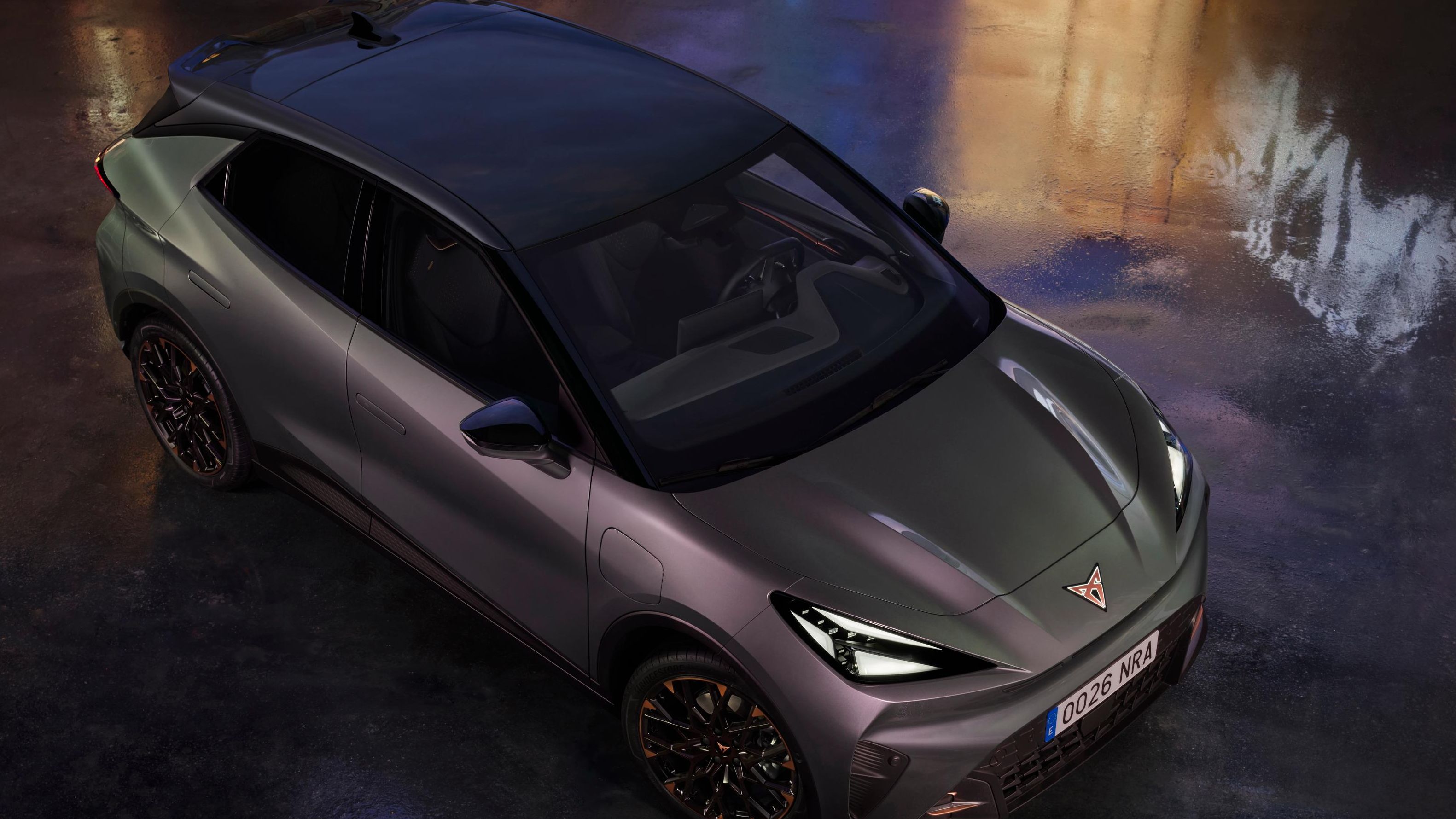 CUPRA Raval je prikazan iz ptičje perspektive na mokri podlagi z odsevi mestnih luči. Oznaka »Red Dot Winner 2026« poudarja nagrajeni dizajn vozila.