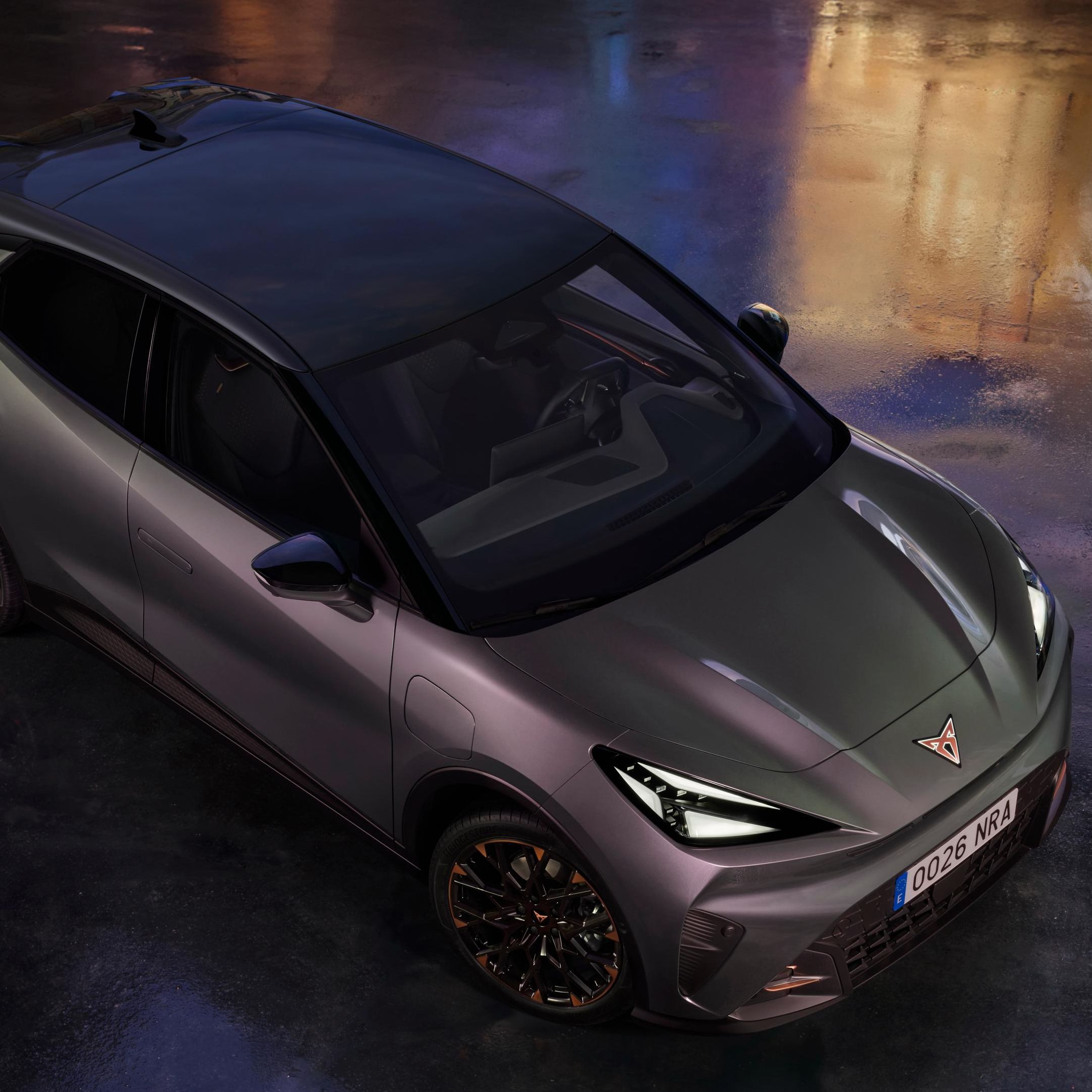 CUPRA Raval je prikazan iz ptičje perspektive na mokri podlagi z odsevi mestnih luči. Oznaka »Red Dot Winner 2026« poudarja nagrajeni dizajn vozila.