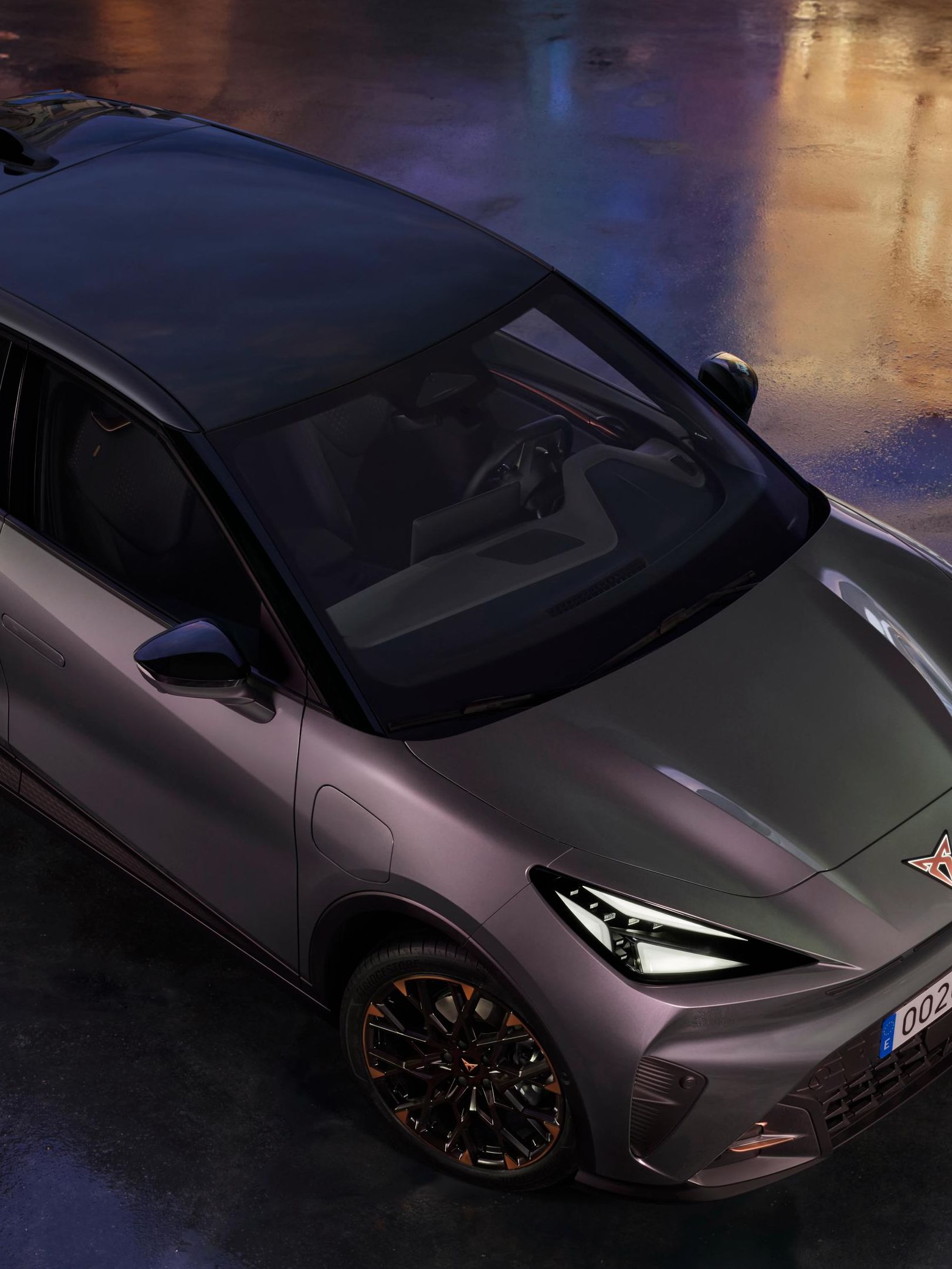 CUPRA Raval je prikazan iz ptičje perspektive na mokri podlagi z odsevi mestnih luči. Oznaka »Red Dot Winner 2026« poudarja nagrajeni dizajn vozila.