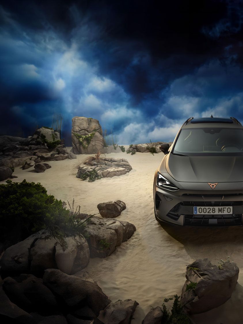 Cupra Formentor stoji na peščenem brezpotju, obdan z kamenjem, pri dramatičnem nebu v ozadju.