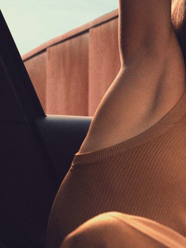 Notranjost avtomobila CUPRA Born s sodobnim vmesnikom na zaslonu na dotik, ki prikazuje različne aplikacije in možnosti. Ženska sedi na voznikovem sedežu v dratatičnem položaju. 