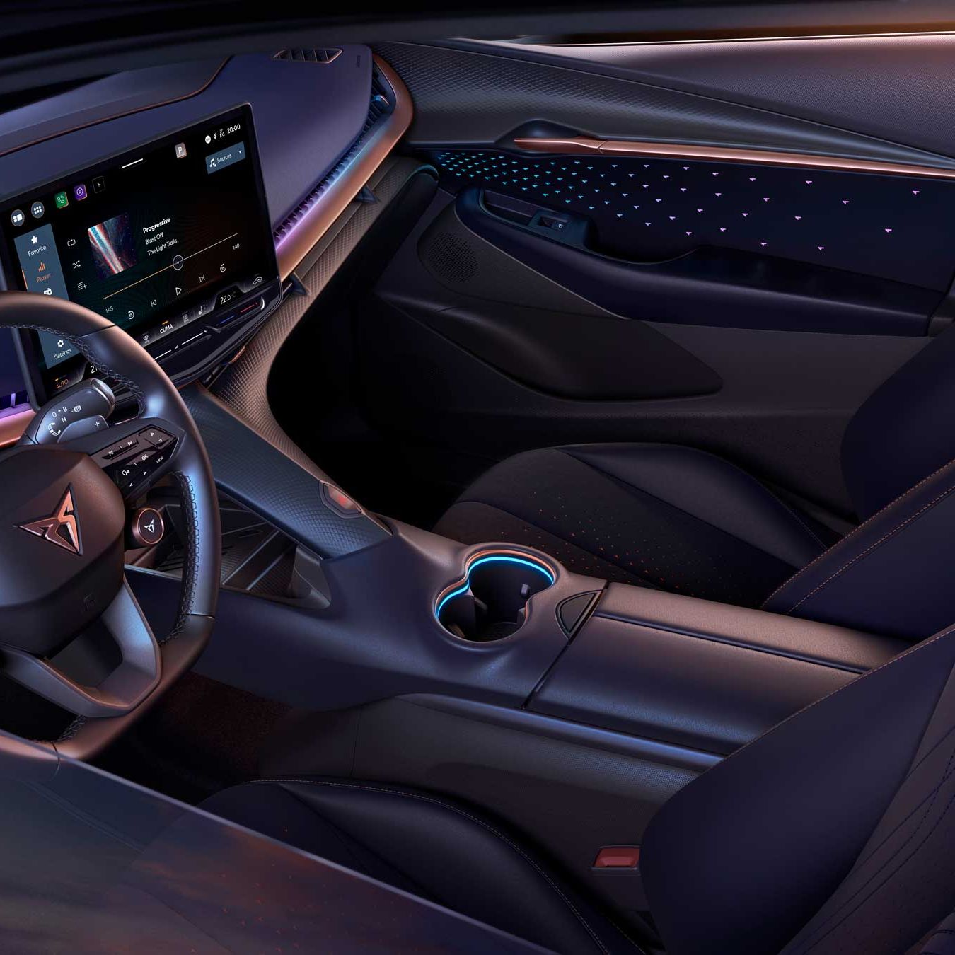 Notranjost sodobnega avtomobila Cupra Tavascan z osvetljenimi podrobnostmi, velikim zaslonom na dotik na sredini armaturne plošče in elegantno oblikovanimi sedeži. Osvetlitev je modra in vijolična, kar dodaja futuristični videz. Na volanu je logotip, osvetljen z modro barvo.