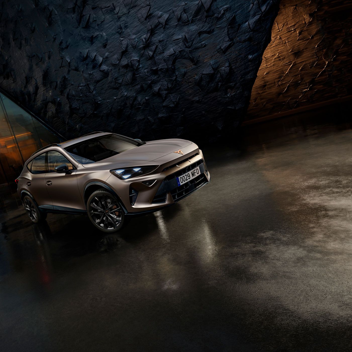 CUPRA Formentor PA v futurističnem okolju zatemnjenih tonov. Avto je parkiran na temnem, zrcalno gladkem tleh pred stavbo s teksturo stene. V ozadju je mestno obzorje ob sončnem zahodu.