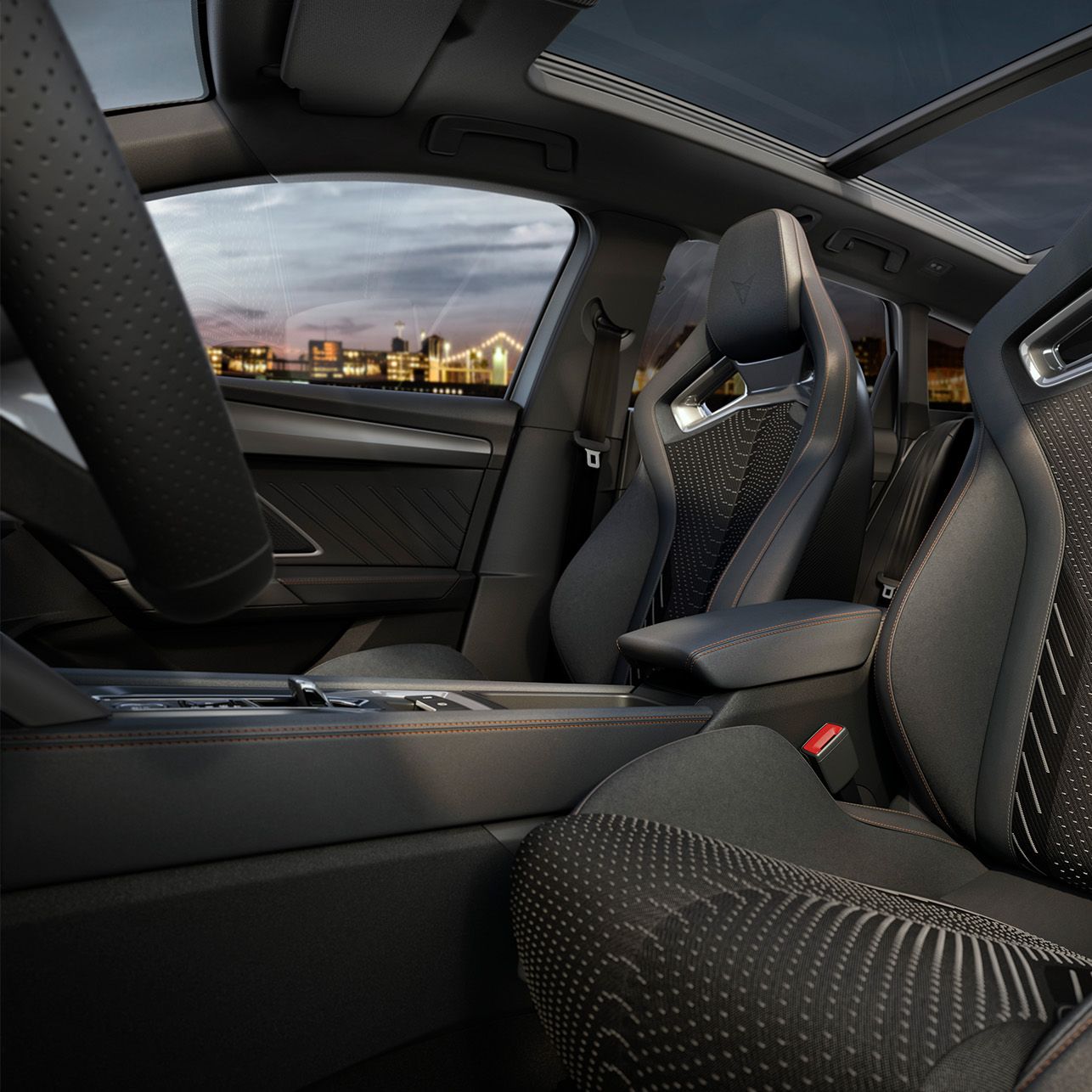 Notranjost moderne avtomobilske kabine CUPRA LEON SPORTSTOURER z dvema sprednjima sedežema, ki imata športni dizajn in detajle iz ogljikovih vlaken. Streha je panoramska in razkriva mestno pokrajino v ozadju med sončnim zahodom. Kabina je opremljena z elegantnimi materiali in prilagodljivimi funkcijami.