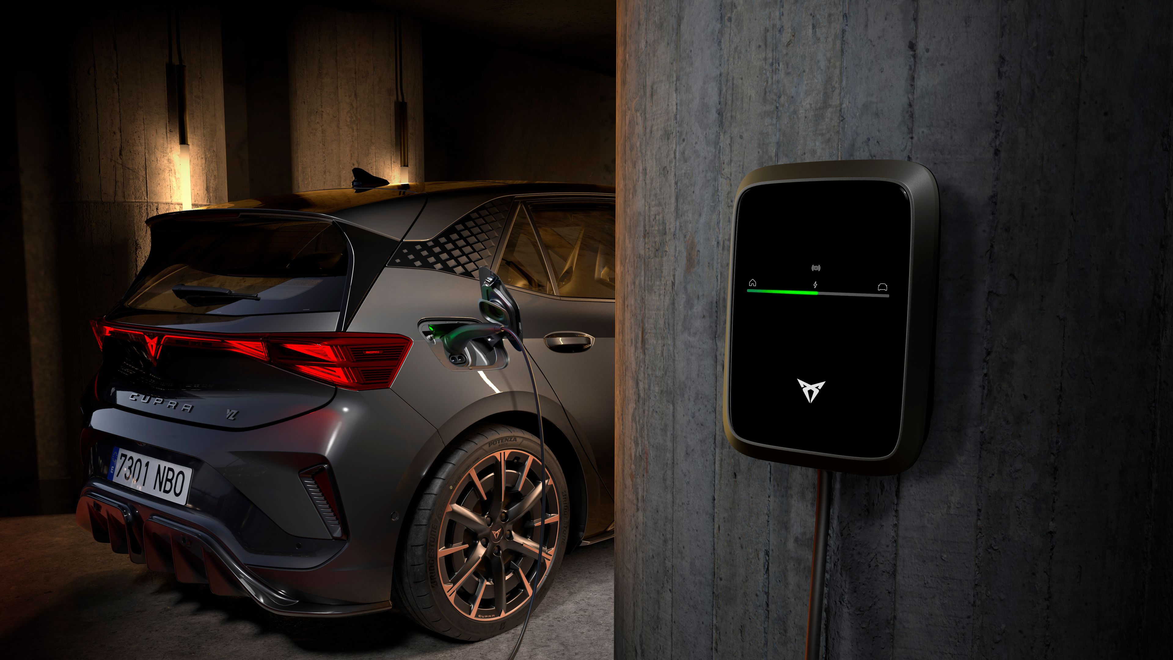 Električni športni CUPRA Born je parkiran v temni garaži in priključen na stensko polnilno postajo.