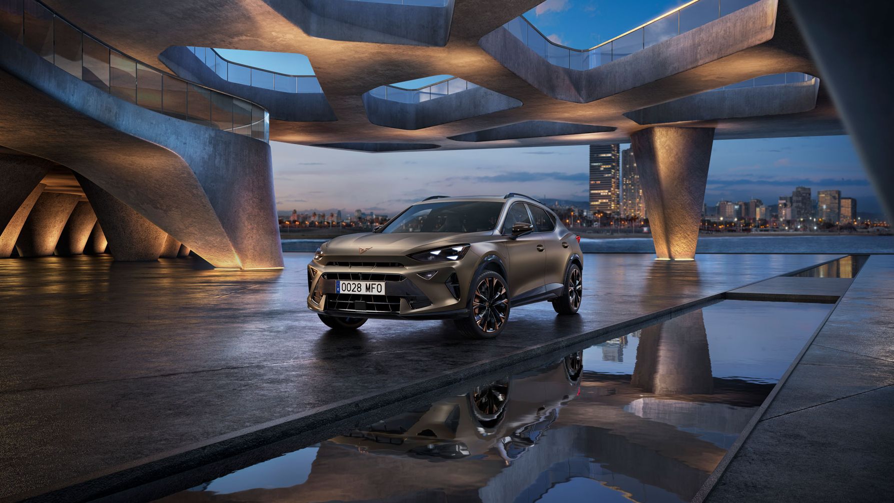 Parkiran CUPRA Formentor PA na zunanjem sodobnem parkirišču z zanimivo arhitekturo. V ozadju se vidi mestna panorama ob reki. Nebo je modro ob sončnem zahodu.