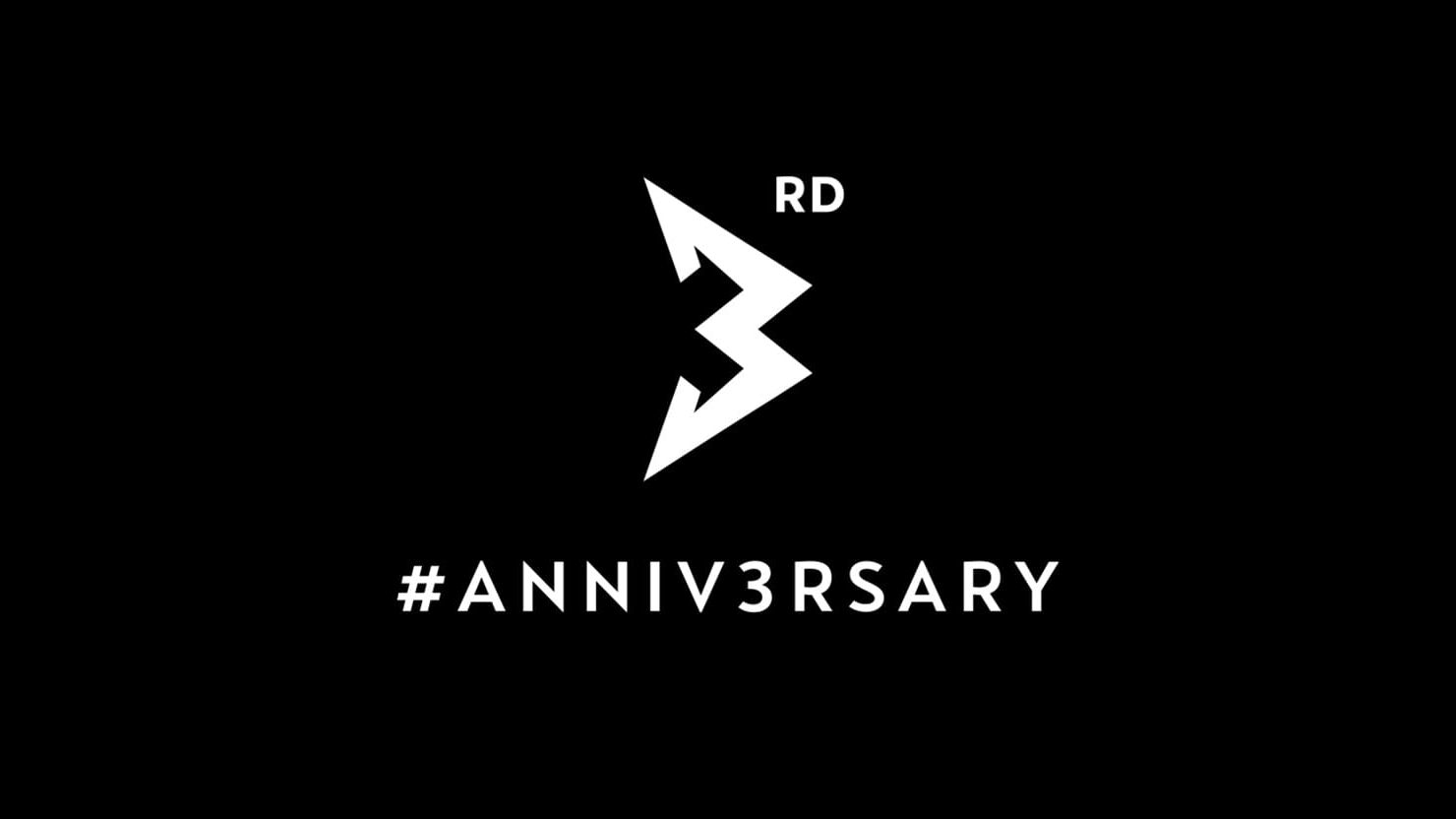 Napis "3rd #ANNIV3RSARY" v beli barvni na črnem ozadju. Številka 3 je prikazana kot logotip v obliki puščice v sredini slike, zgoraj desno je manjši tekst "RD", spodaj pa #ANNIV3RSARY. 