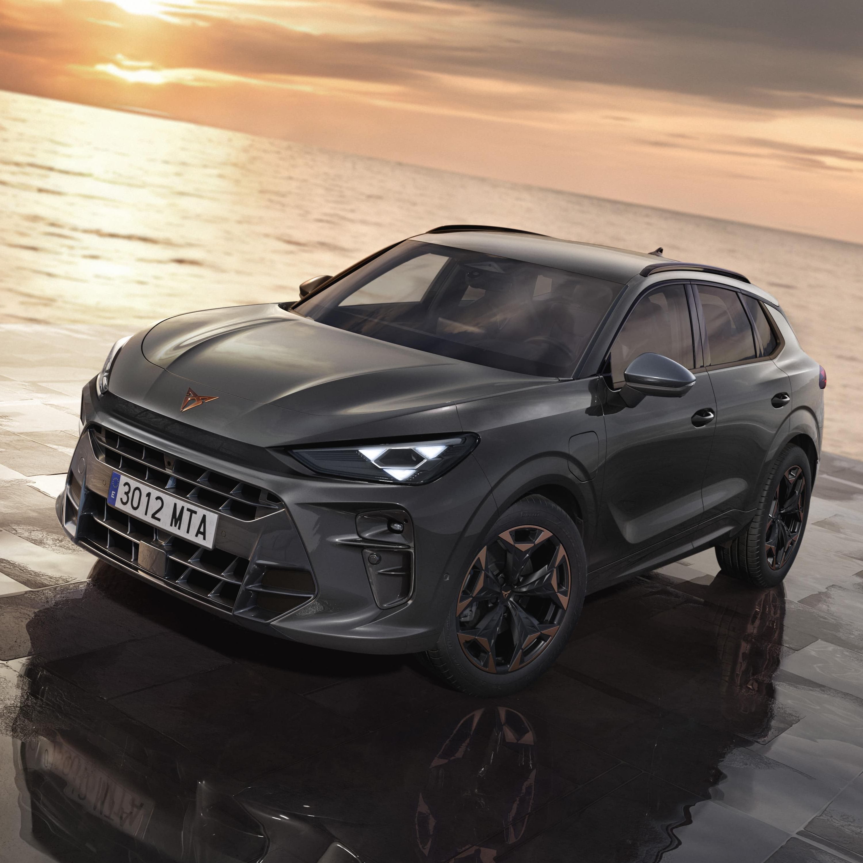 CUPRA Terramar je parkiran na tlakovani površini ob morju ob sončnem zahodu. Avto ima sodoben dizajn in črna platišča.