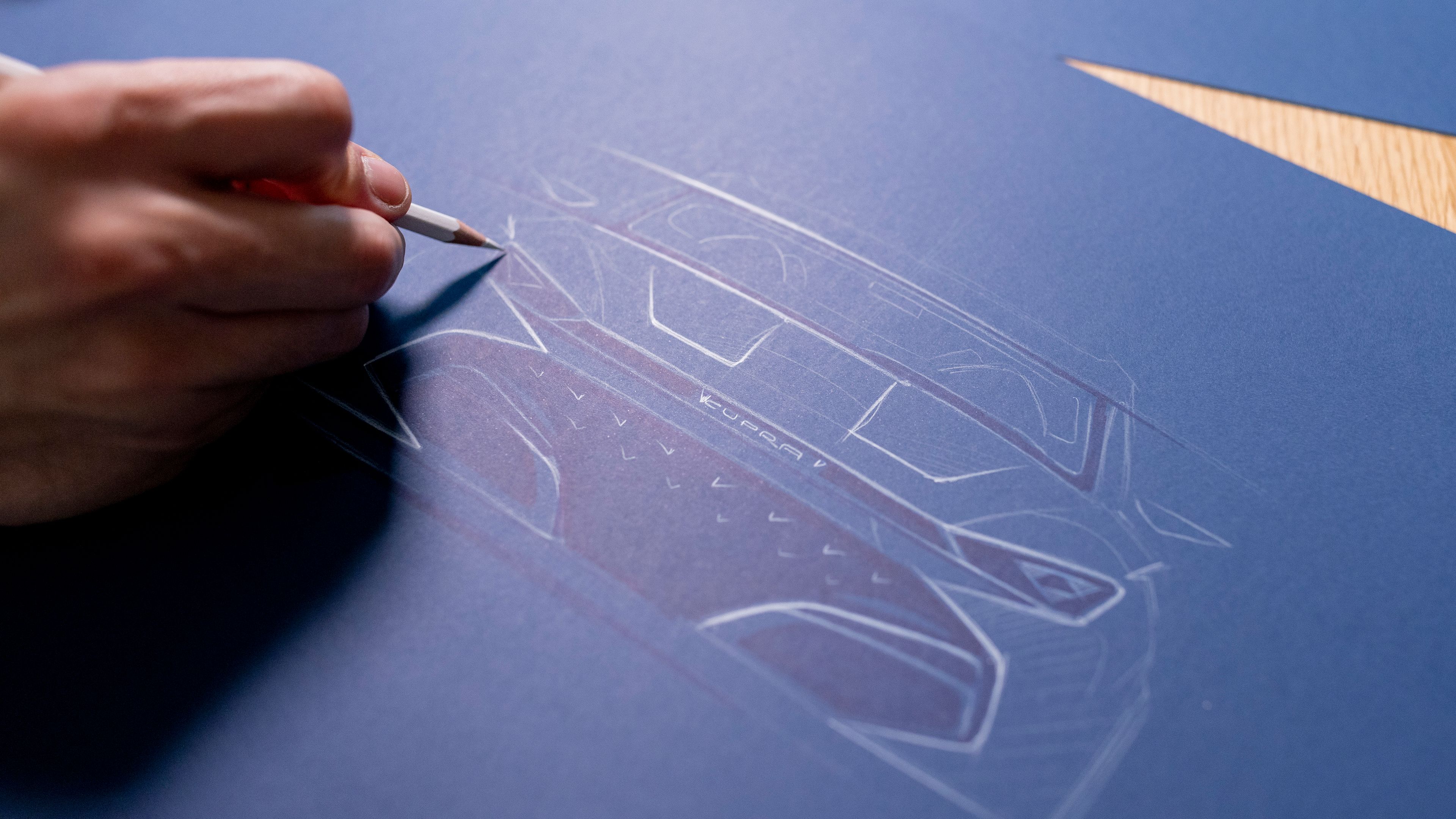 Roka drži beli svinčnik nad modrim papirjem, na katerem je načrt avtomobila CUPRA Tavascan.