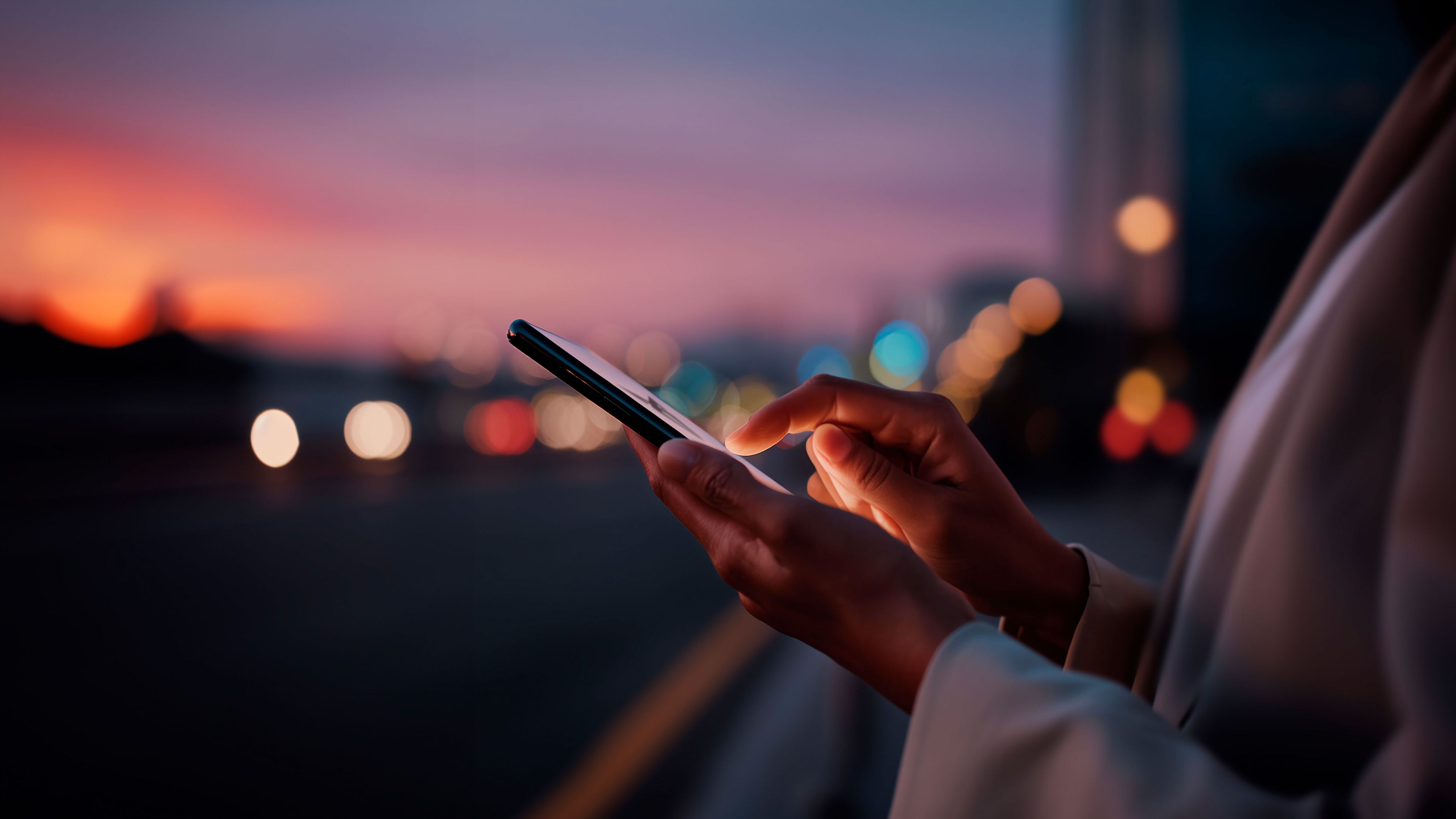 Eine Person hält draußen ihr Smartphone, um zu zeigen, dass du dein Auto von überall aus nach deinen Vorlieben einrichten kannst.