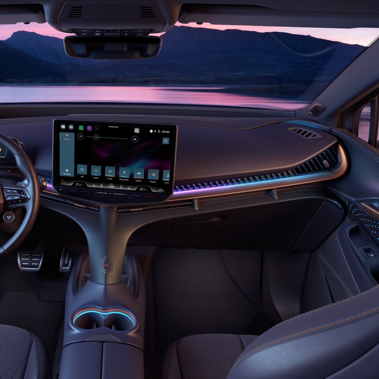 Notranjost sodobnega avtomobila Cupra Tavascan s futurističnim dizajnom, osvetljenimi linijami in velikim zaslonom na dotik na armaturni plošči. Okoli volana in sedežev je mehka, elegantna obloga. V ozadju je pogled na jezero in gore ob sončnem zahodu.