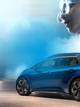 Cupra Born, modra športna limuzina vozi skozi moder tunel. V ozadju je voda, ki se dviga v zrak. V zgornjem desnem kotu je bel logo podoben puščici.