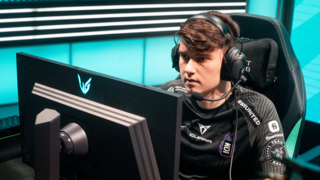 Moški sedi za računalnikom in nosi slušalke med igranjem videoigre. 