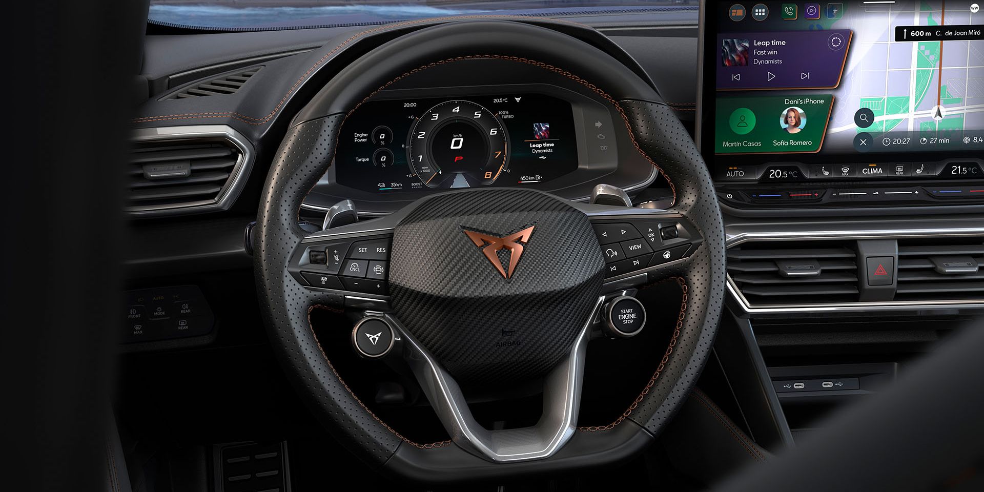 Notranjost avtomobila Cupra Formentor prikazuje volan znamke Cupra ter del armaturne plošče z dvema digitalnima zaslonoma. Zaslon na volanu prikazuje informacijski sistem avtomobila, medtem ko desni zaslon prikazuje navigacijo. V ozadju je pogled na mesto ob morju.