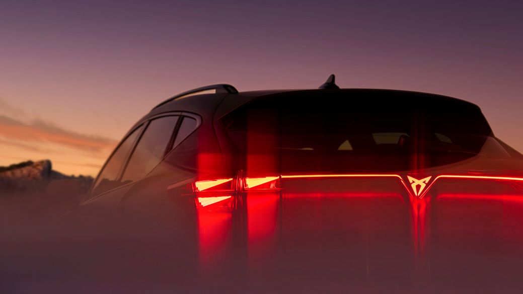 Zadnji del avtomobila CUPRA Formentor, med sončnim zahodom, z osvetljenimi rdečimi zadnjimi lučmi.