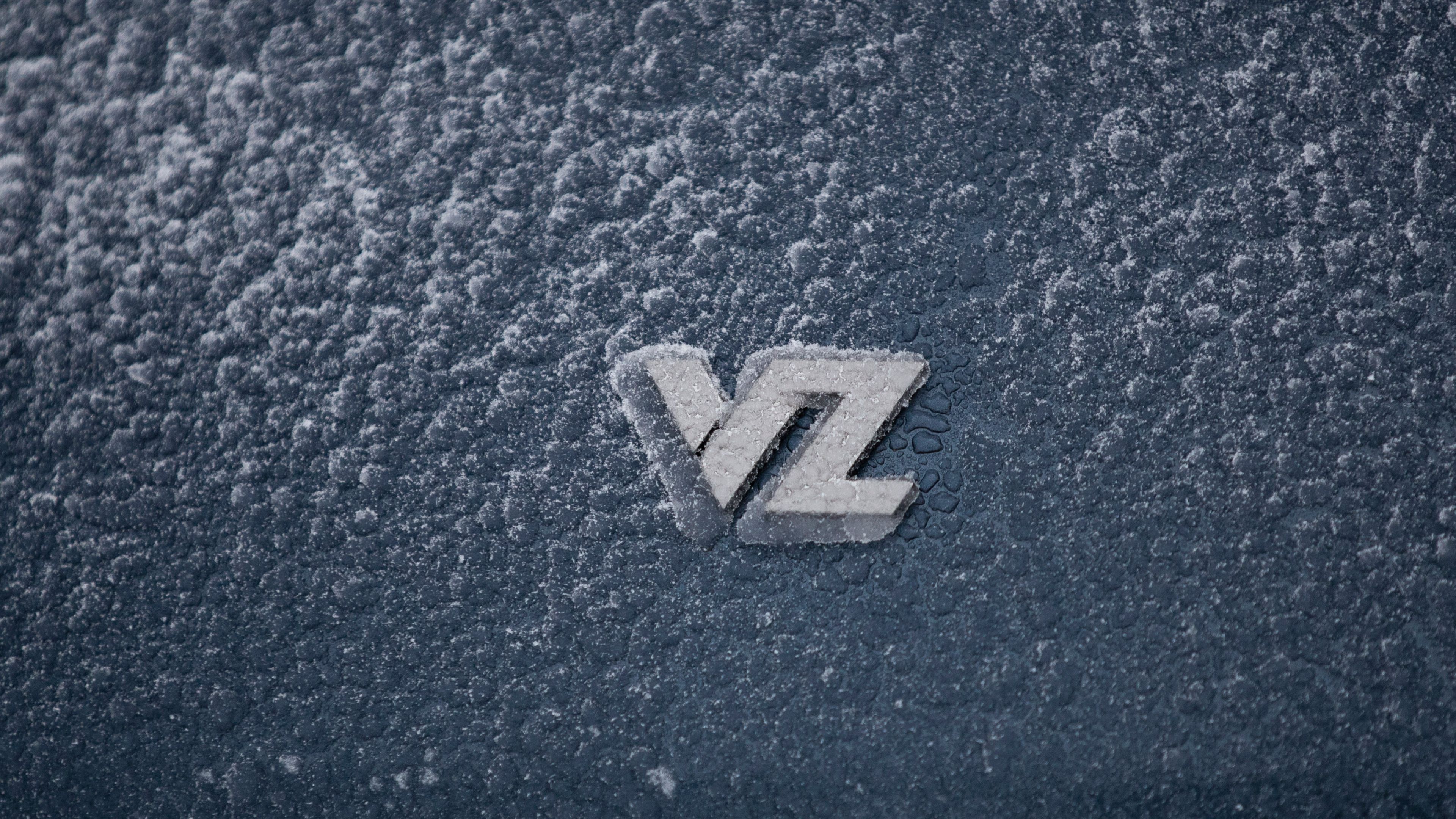 Logotip "VZ" na zaledeni površini avtomobila CUPRA. Površina je pokrita s snežno plastjo.