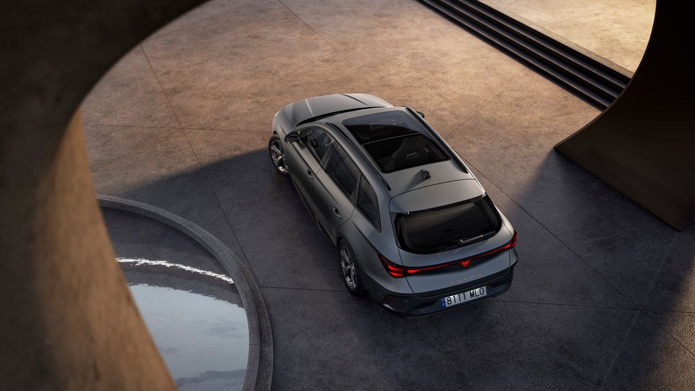 Sodobni srebrno CUPRA Leon Sportstoureparkiran na betonski površini, fotografiran iz ptičje perspektive. Okoli vozila so arhitekturni betonski loki ter majhen vodni bazen, kar ustvarja minimalistično, moderno okolje.