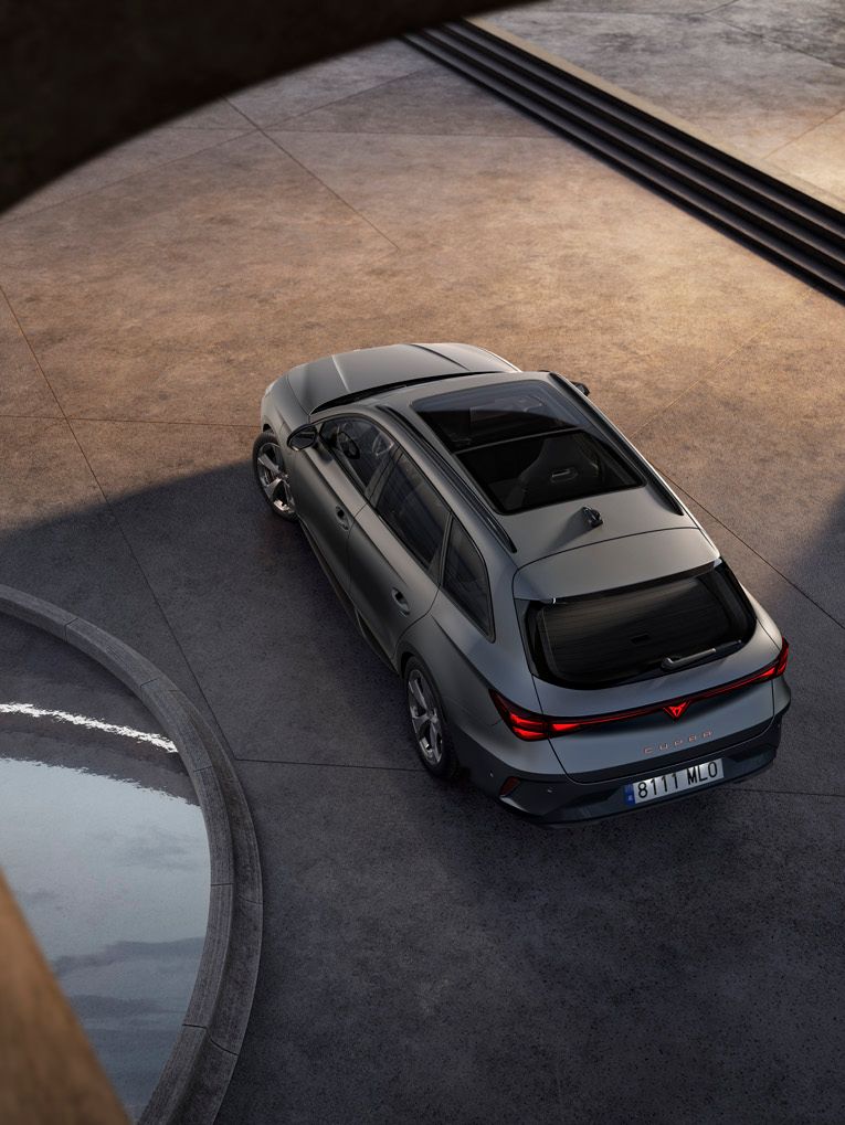 Sodobni srebrno CUPRA Leon Sportstoureparkiran na betonski površini, fotografiran iz ptičje perspektive. Okoli vozila so arhitekturni betonski loki ter majhen vodni bazen, kar ustvarja minimalistično, moderno okolje.