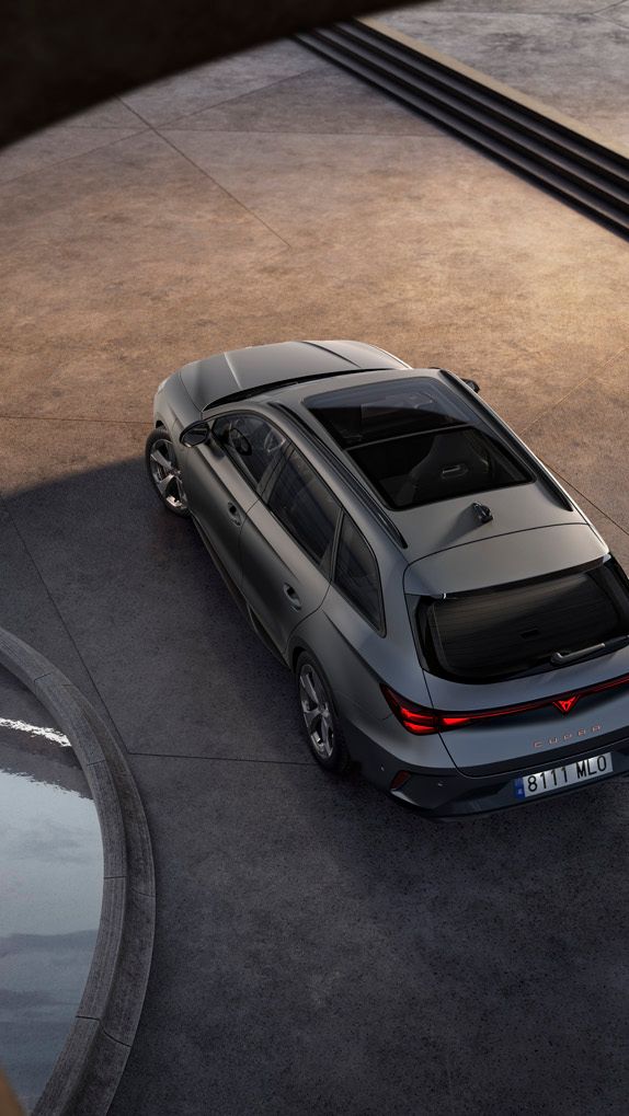 Sodobni srebrno CUPRA Leon Sportstoureparkiran na betonski površini, fotografiran iz ptičje perspektive. Okoli vozila so arhitekturni betonski loki ter majhen vodni bazen, kar ustvarja minimalistično, moderno okolje.