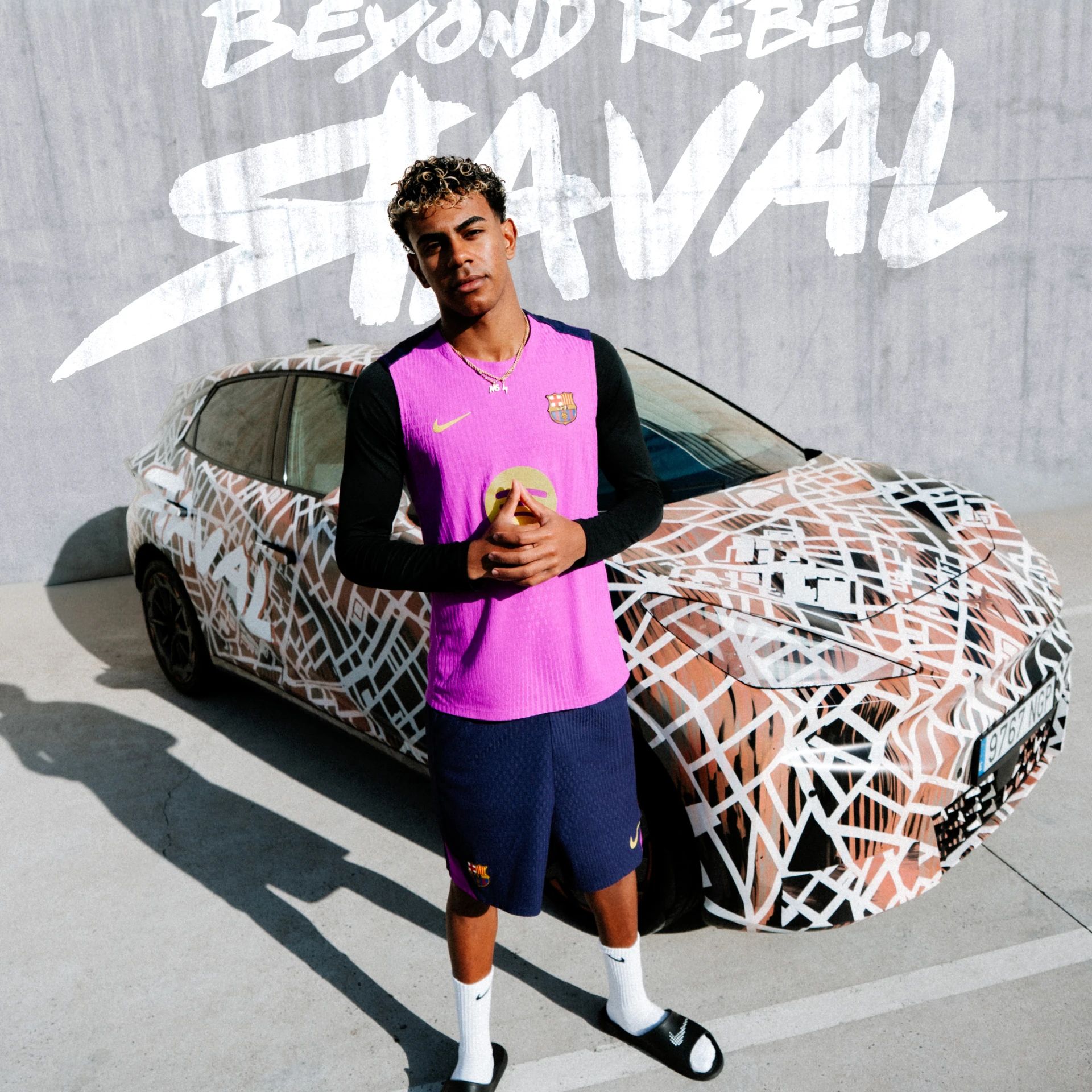 Nogometaš FC Barcelone v roza dresu stoji pred CUPRA Raval vozilom. V ozadju napis: BEYOND REBEL, RAVAL.
