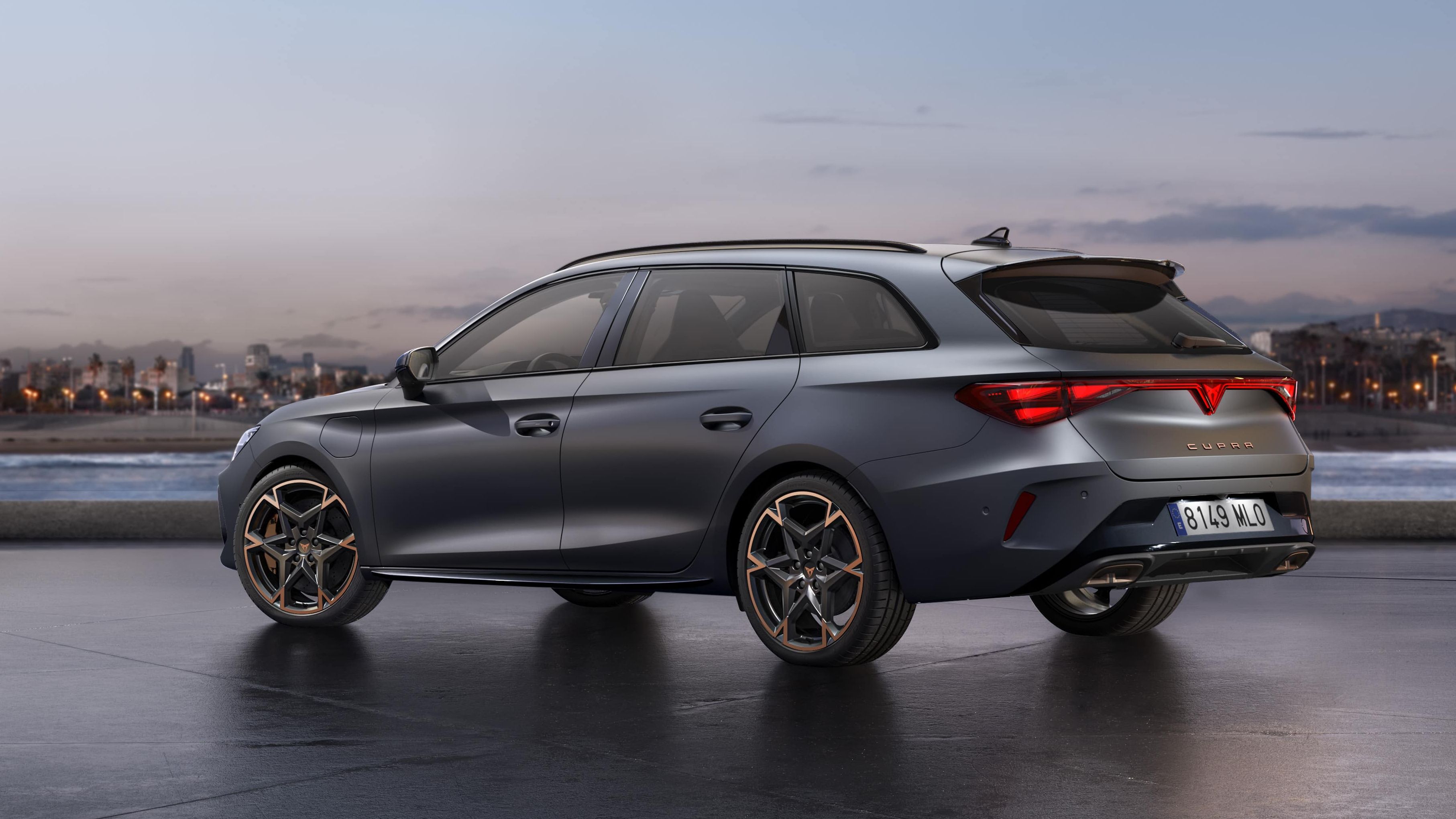 CUPRA LEON SPORTSTOURER stoji ob obali ob sončnem zahodu. V ozadju je mestno obzorje z visokimi stavbami, mokra površina pod vozilom pa odseva nebo.