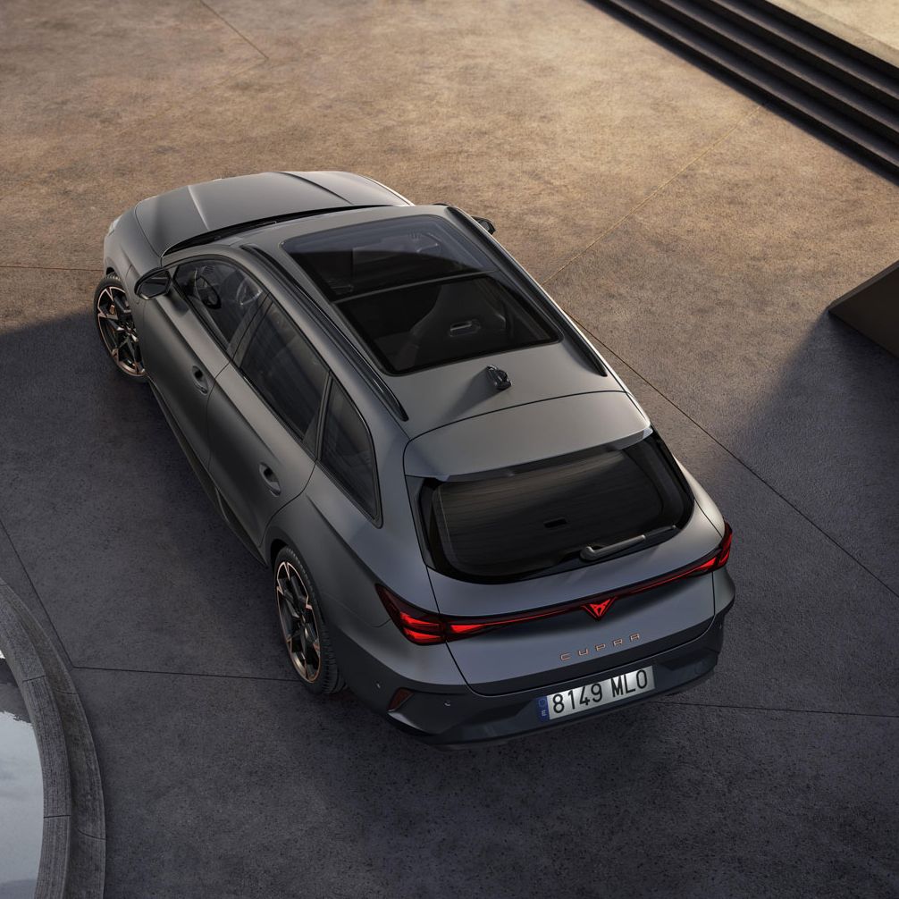 CUPRA LEON SPORTSTOURER VZ parkiran na betonski površini, posnet iz ptičje perspektive. Avto je temno sive barve, okoli njega pa so betonski stebri in majhen bazen z vodo. V ozadju so stopnice, ki vodijo navzgor.