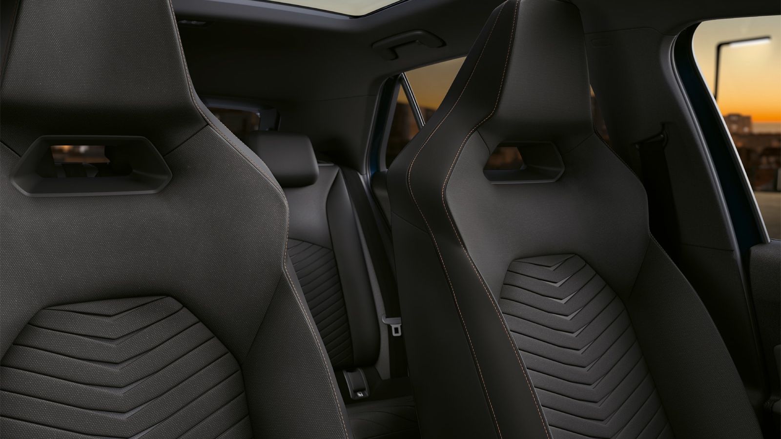 Notranjost avtomobila CUPRA Born z dvema sprednjima sedežema iz črnega usnja in stekleno streho. V ozadju so vidni zadnji sedeži. Avto je parkiran in zunaj se kaže sončni zahod.